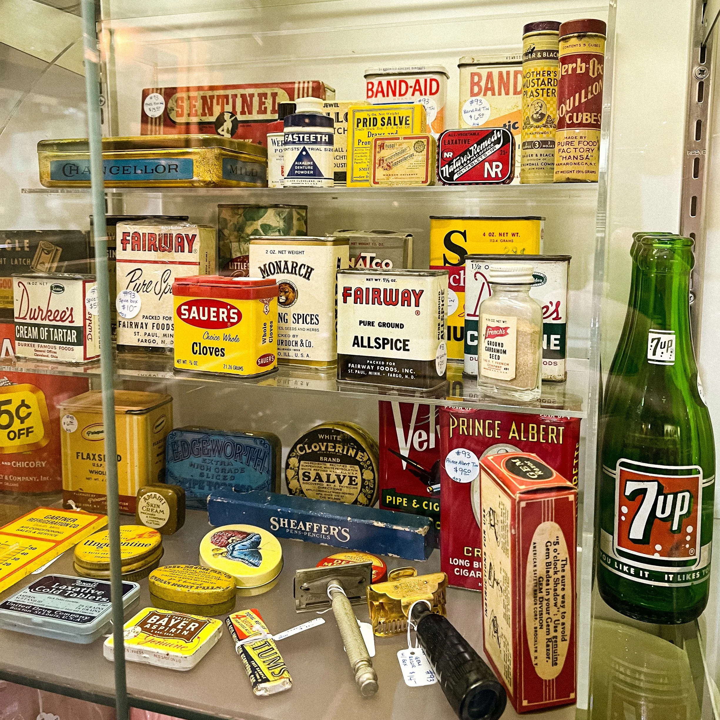 A shelf with various vintage medicine and health products, including tins of bandages, ointments, and medicinal kits.