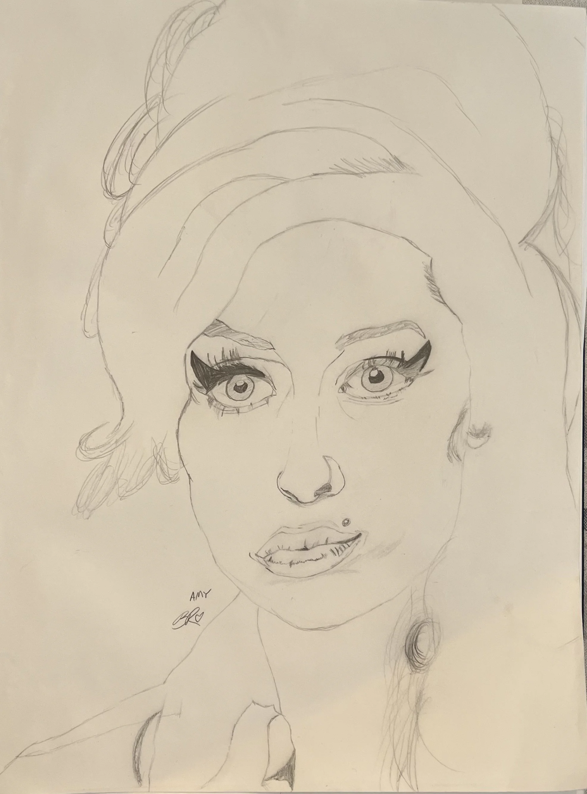 A hand-drawn sketch of a woman’s face with detailed eyes, eyebrows, nose, and lips. She has long, flowing hair and appears to be wearing makeup, with eyeliner and lipstick. The drawing is done in pencil and is signed "AMY" at the bottom with a signature.