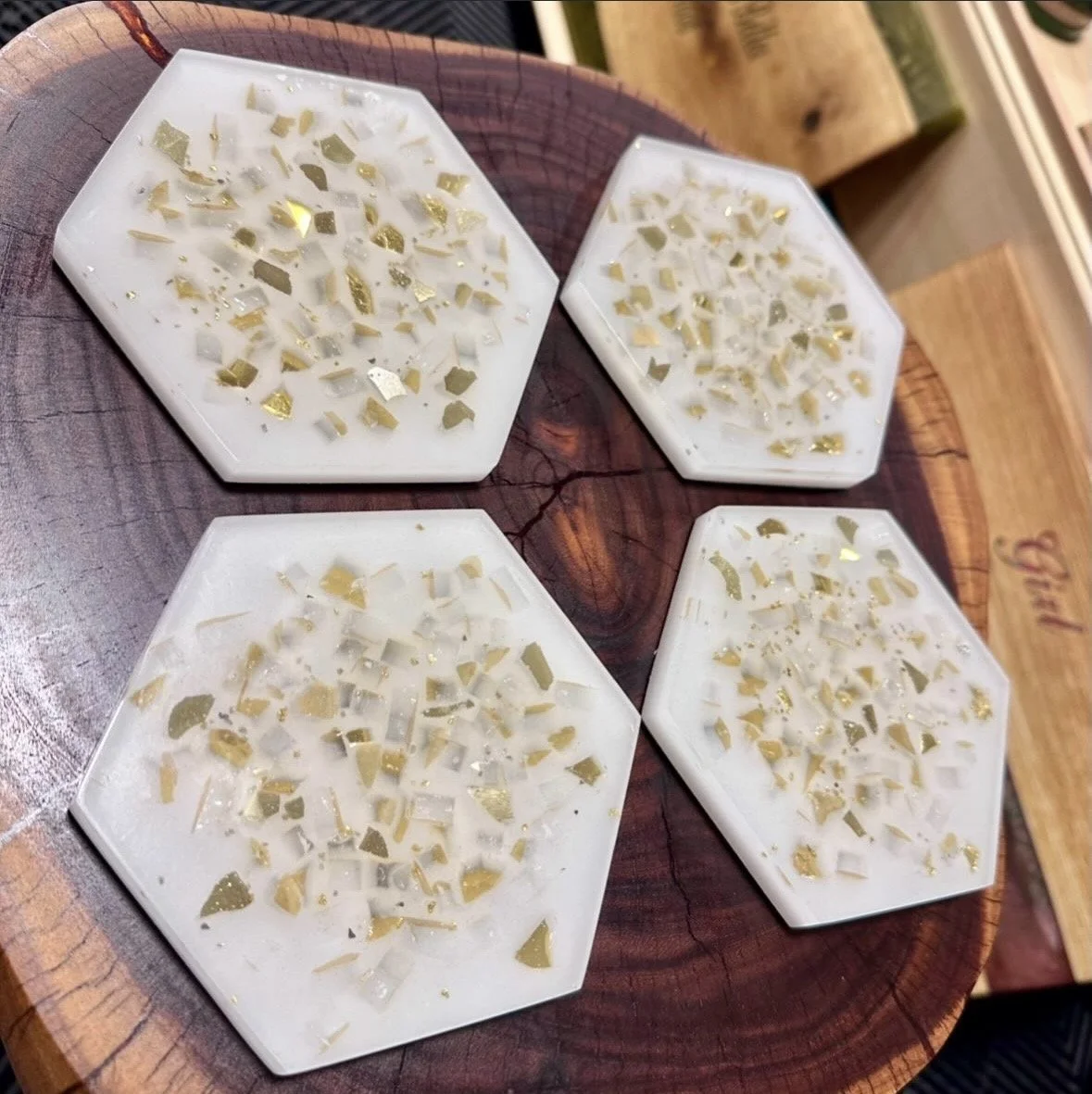 Four hexagonal white coasters with a mosaic of small white and gold pieces.