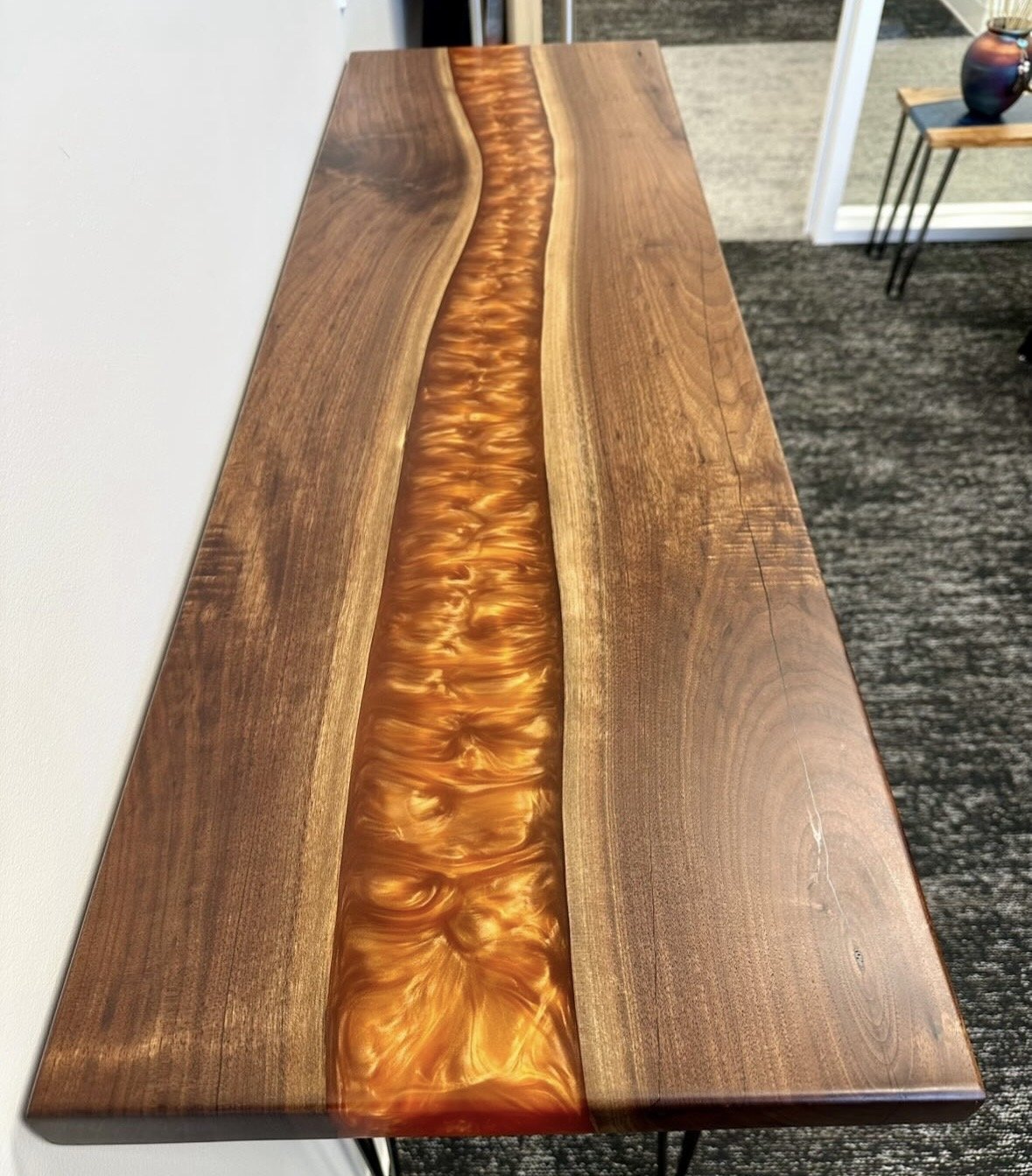 Wooden table with a resin river running through the center, featuring a glossy, swirling amber pattern.