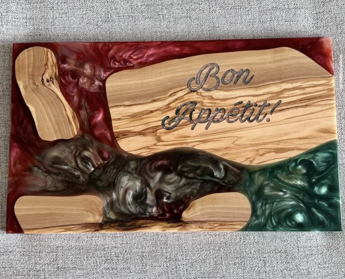 A decorative wooden board with a marbled design and the inscription "Bon Appétit!" engraved on it.