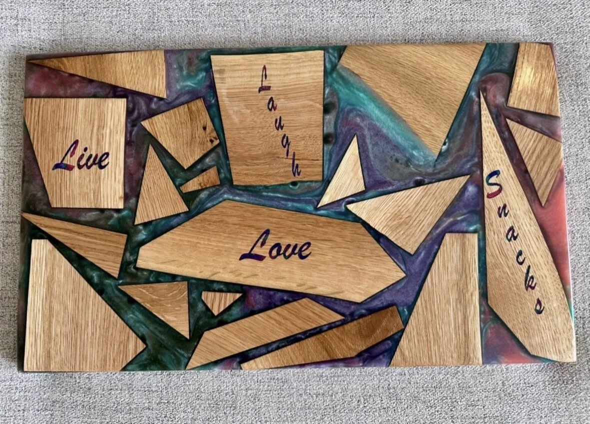 Decorative wooden board with various wooden pieces, some with words like "Live," "Laugh," "Love," and "Snacks" written on them.