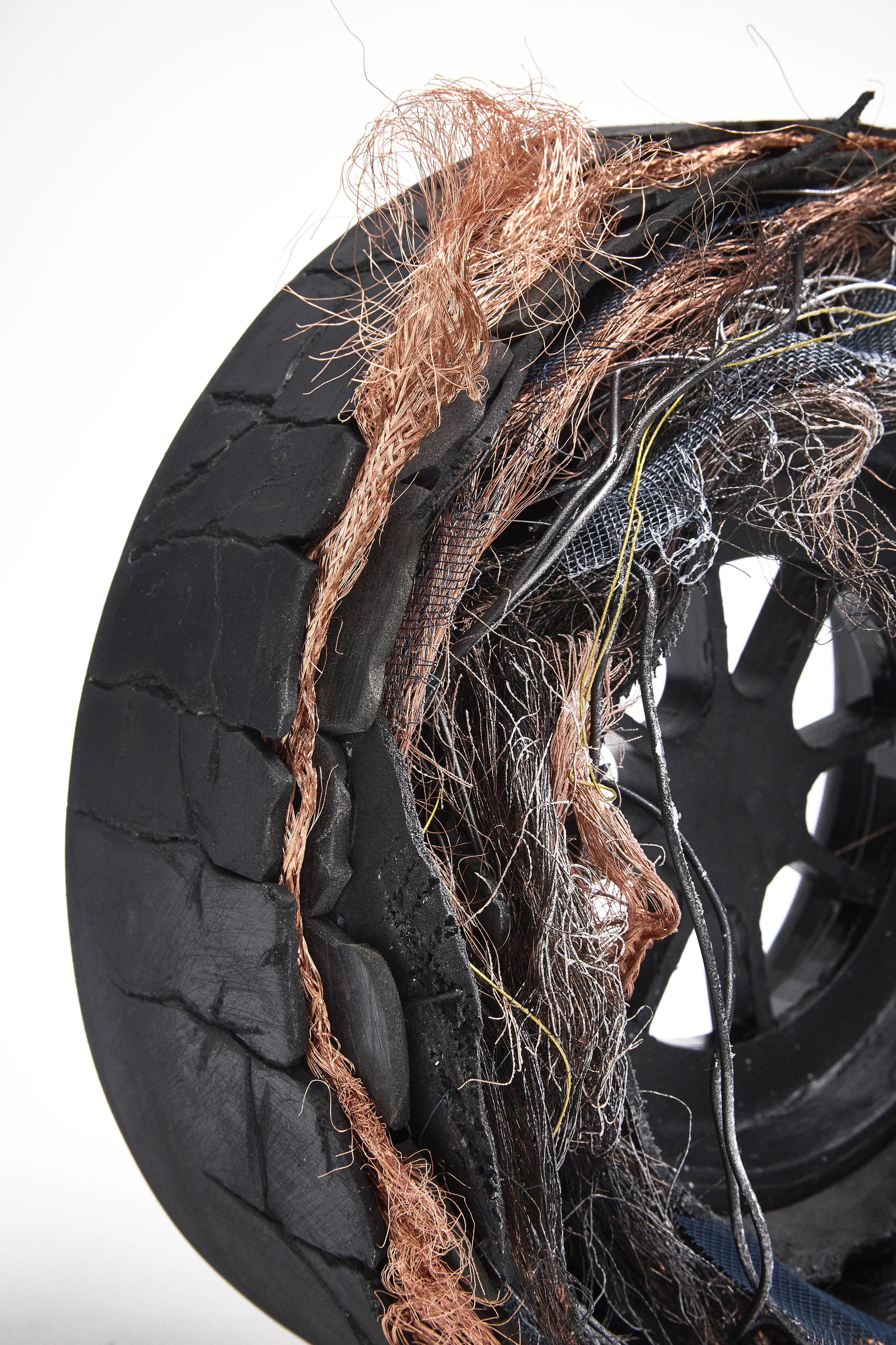 Cross-section of a damaged black rubber track with exposed copper wires, car axle, and worn-out treads.