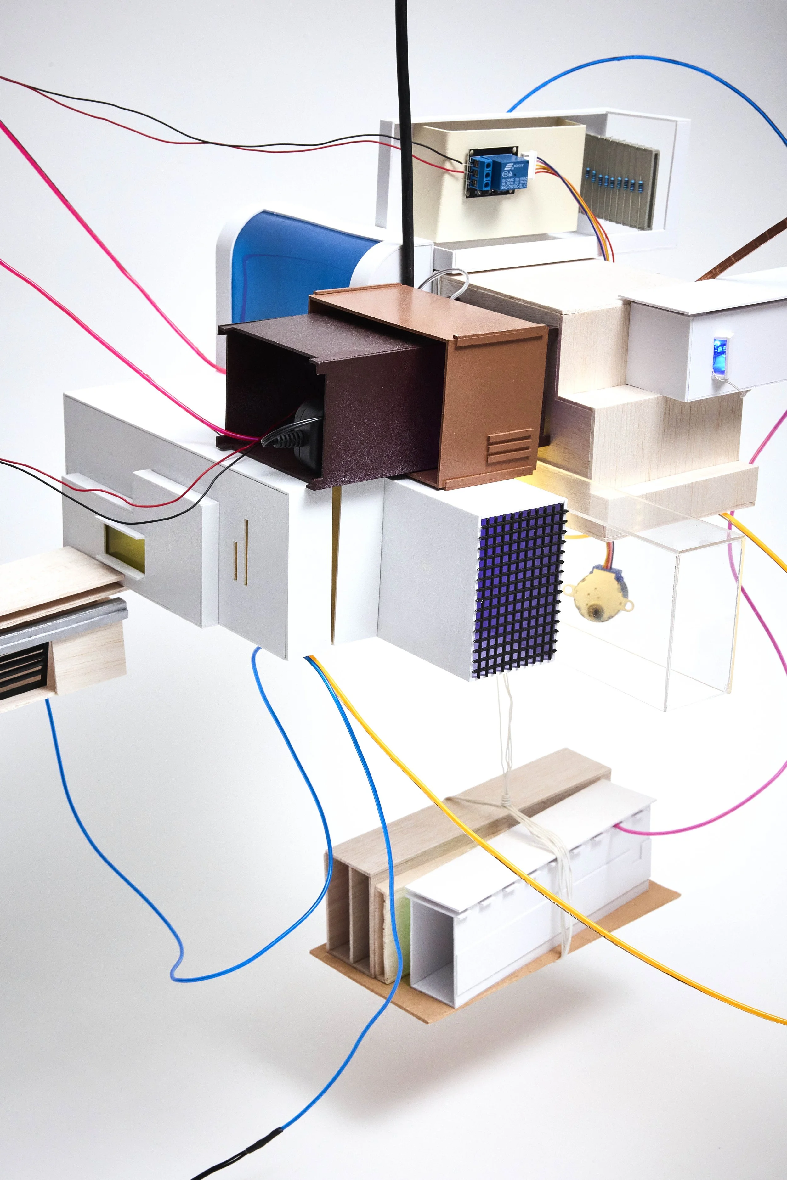 A model of a building made from various materials with wires and electronic components attached.