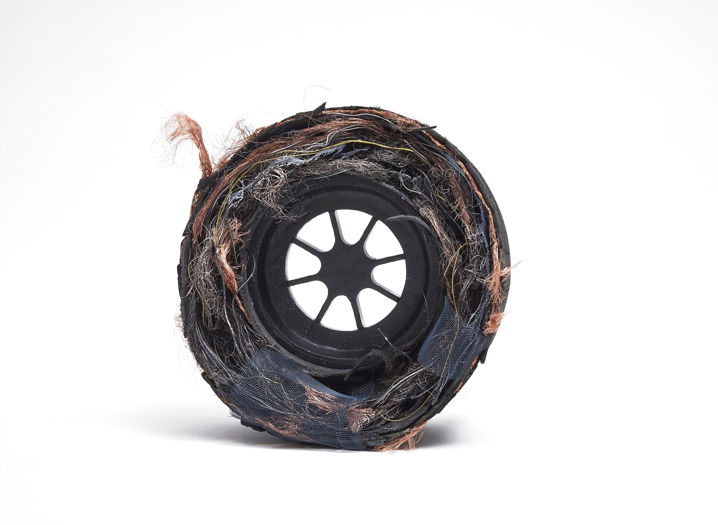 Close-up of a cutaway wire spool with frayed wires and damaged insulation, showing tangled copper and fiber strands inside.