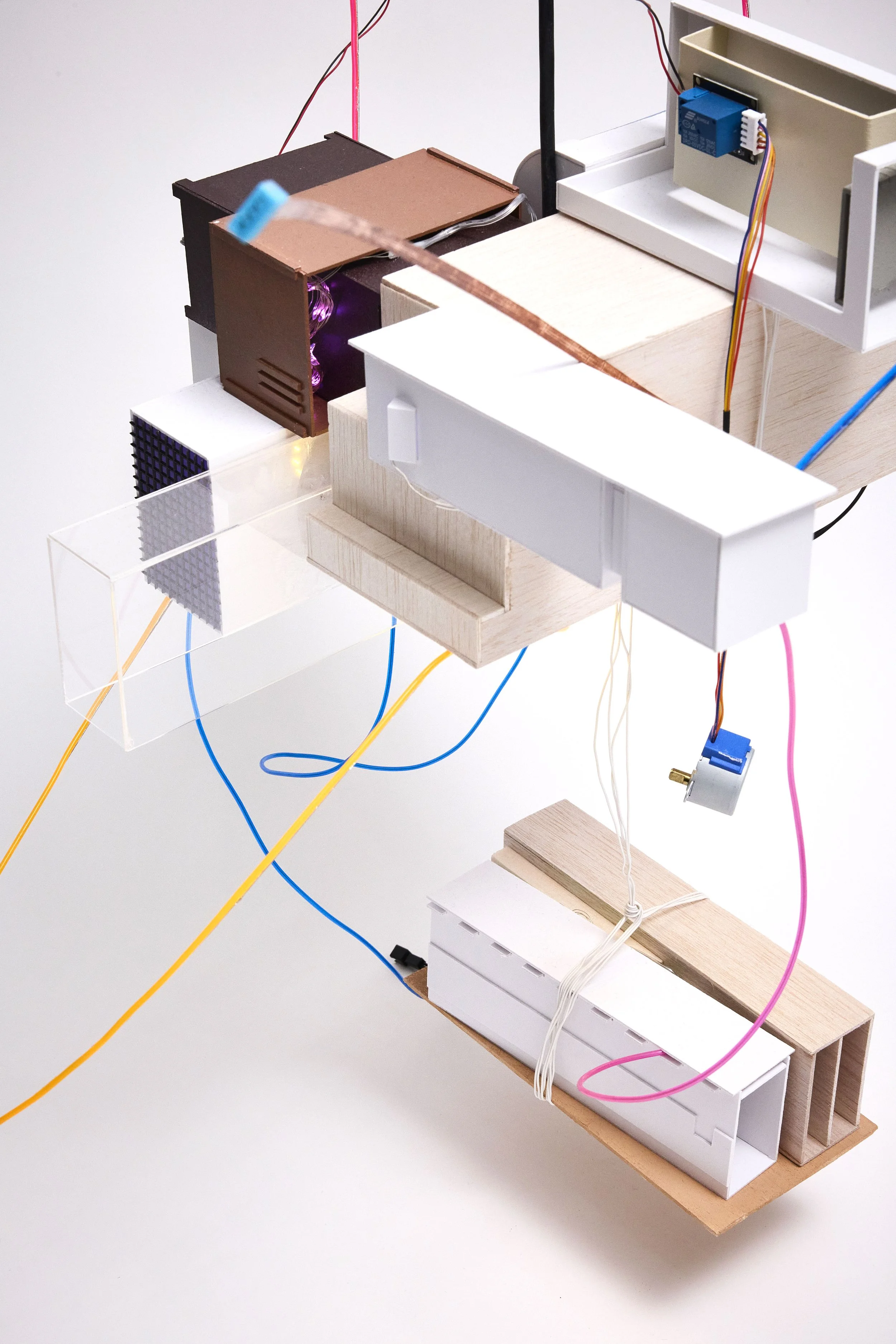 A creative model of a machine or structure made of wooden blocks, white plastic parts, colorful wires, small electronic components, and a purple glowing element, assembled on a white surface.