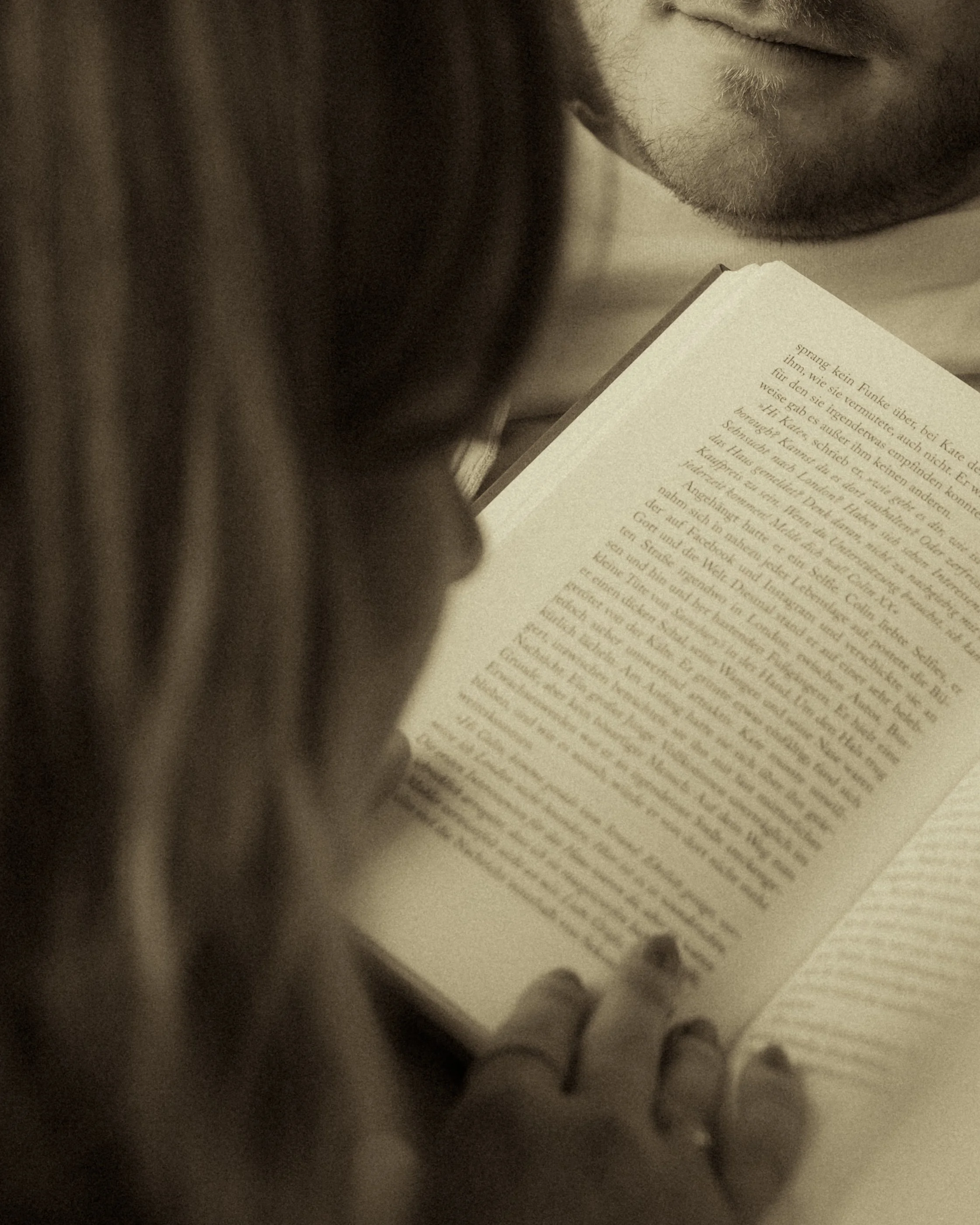 Eine Person liest ein Buch mit Text auf Deutsch. Der Fokus liegt auf den Lippen und dem Buch, das im Vordergrund liegt.