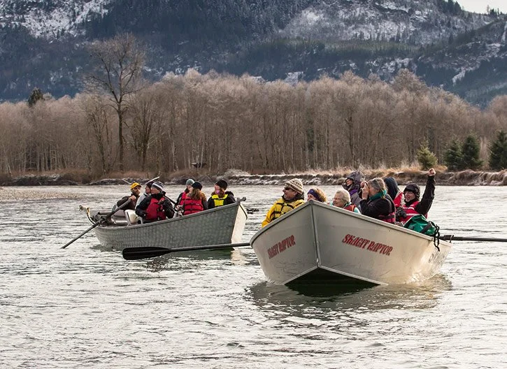 Group of people on two boats in the river.