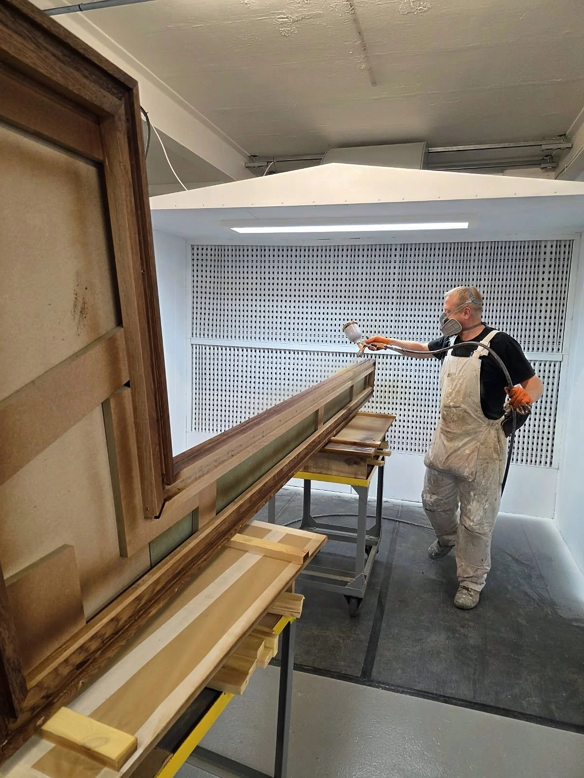 Spray finisher coating a long timber moulding in the spray booth