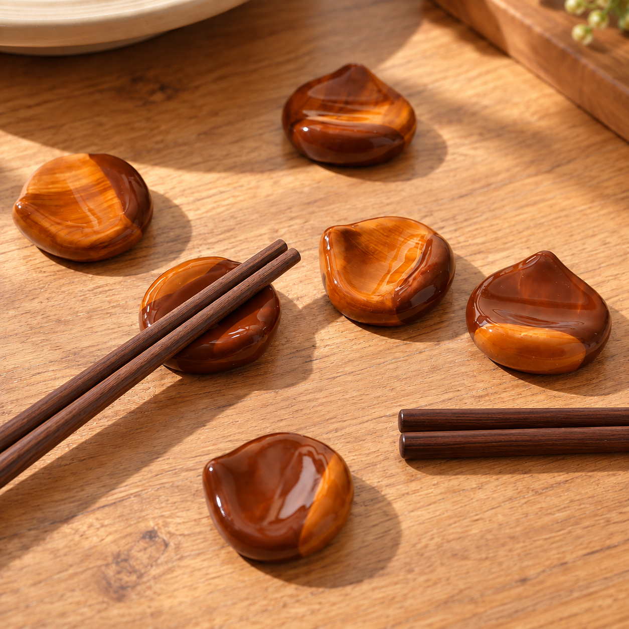 Amber brown ceramic chestnut-shaped chopstick rests displayed on a warm wooden table.