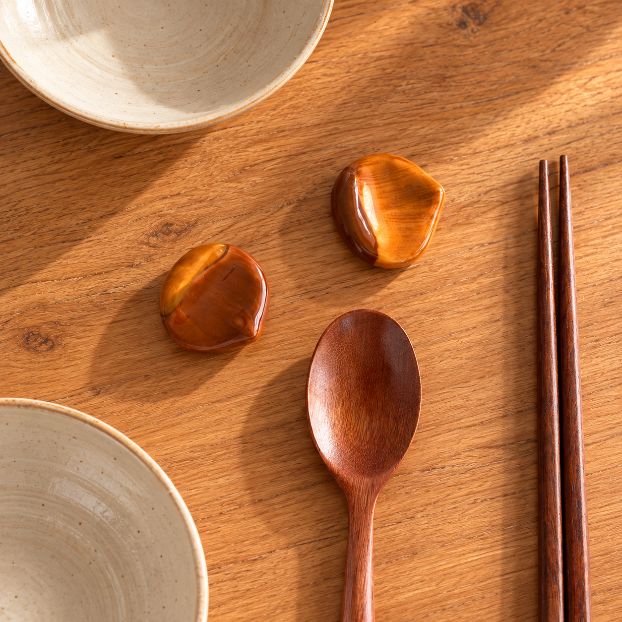 Amber brown ceramic chestnut-shaped chopstick rests displayed on a warm wooden table.