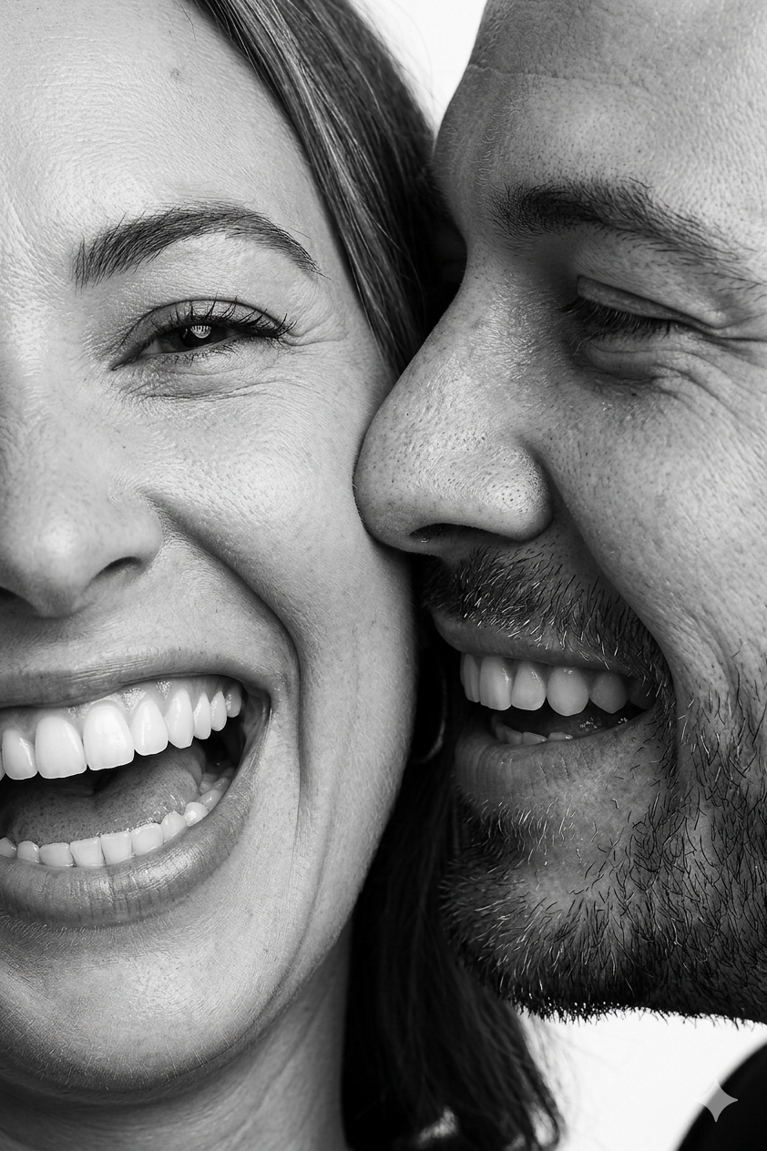 Close-up of a smiling woman and man with eyes closed, faces close together, black and white photo.