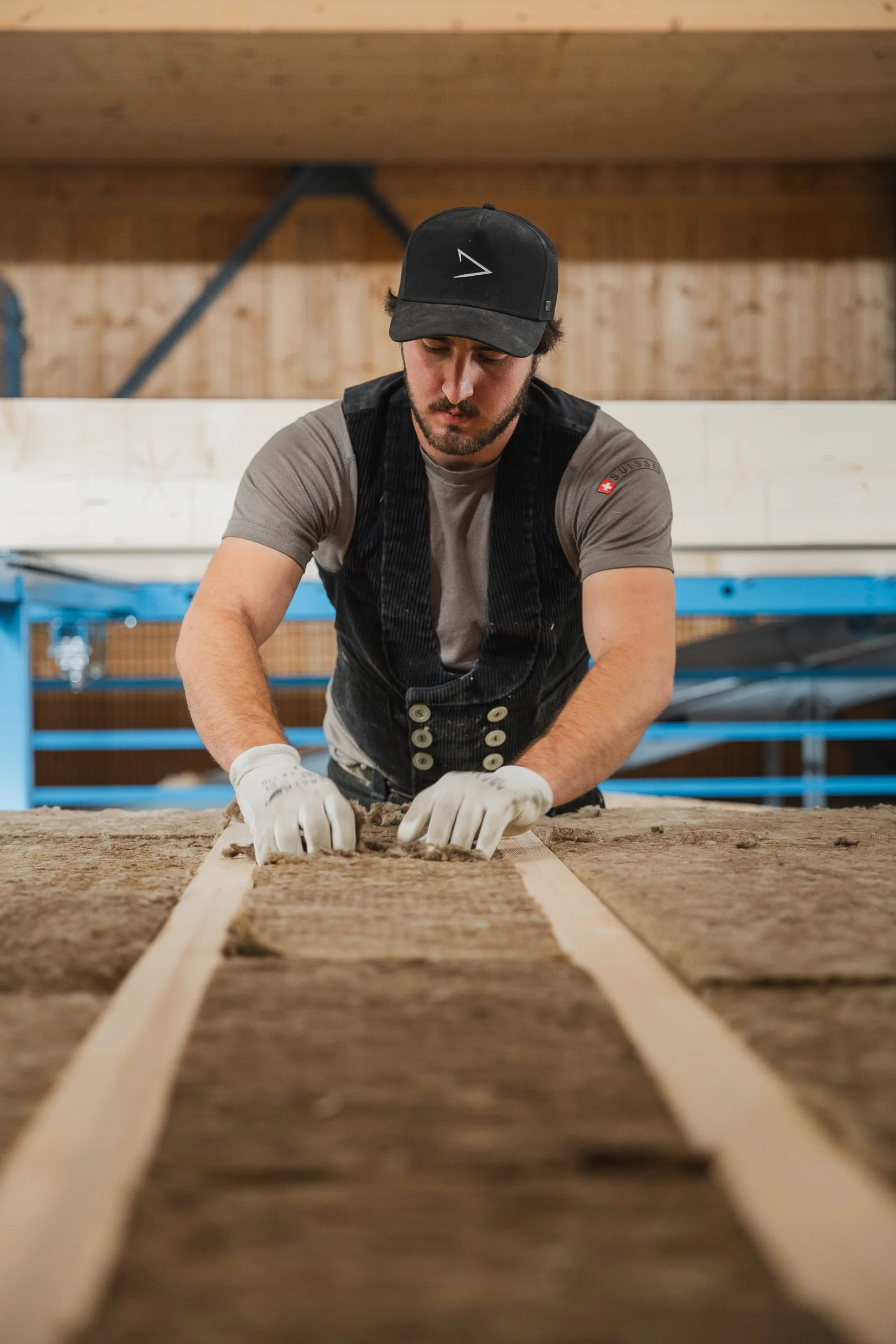 Ein Mann arbeitet in einer Holzwerkstatt und legt Holzstücke auf einen Tisch.