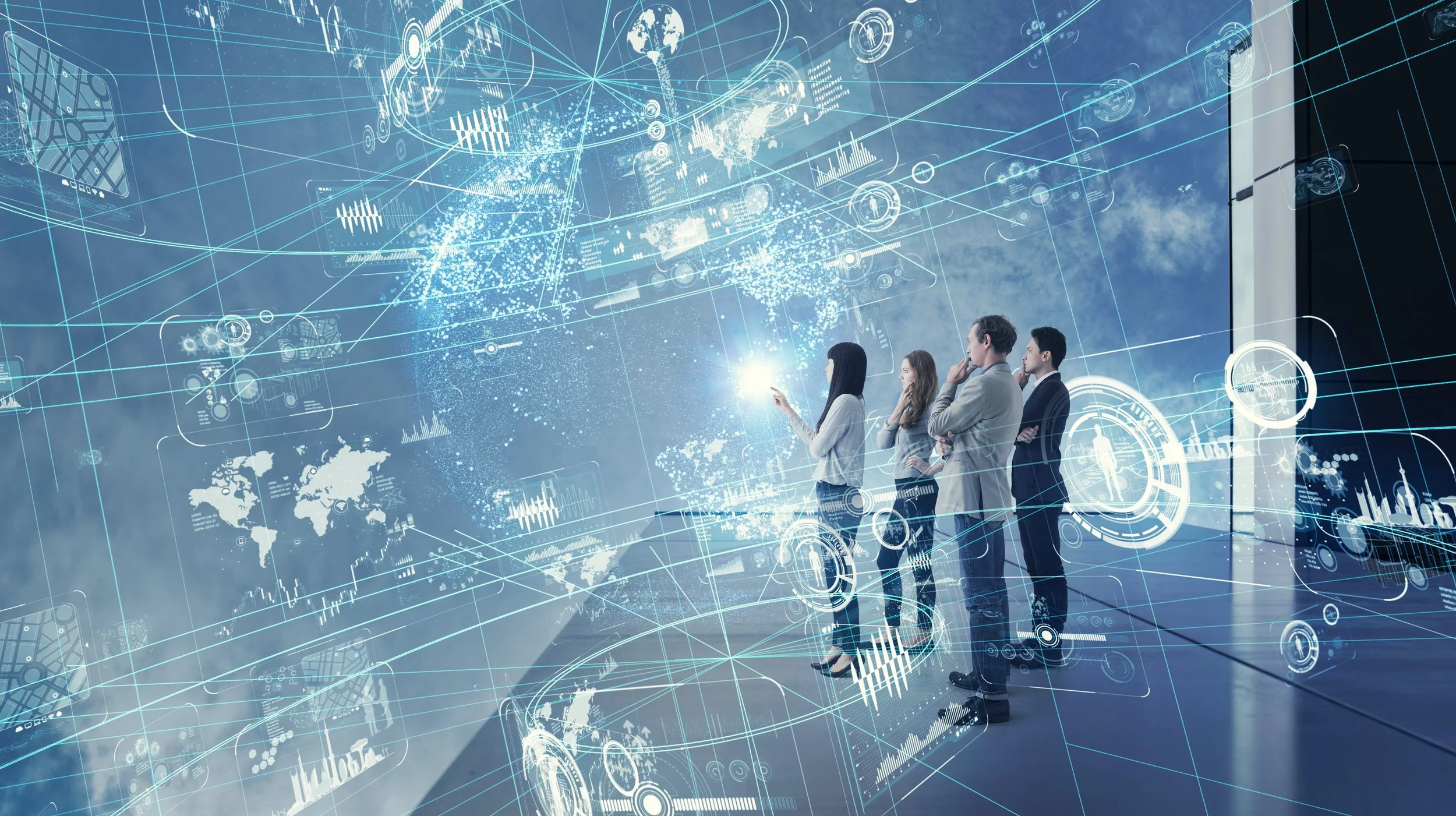 Four business professionals in formal attire standing in front of a large digital display with futuristic graphs, charts, and world maps overlayed with glowing blue lines and icons, illustrating data analysis and technology concepts.