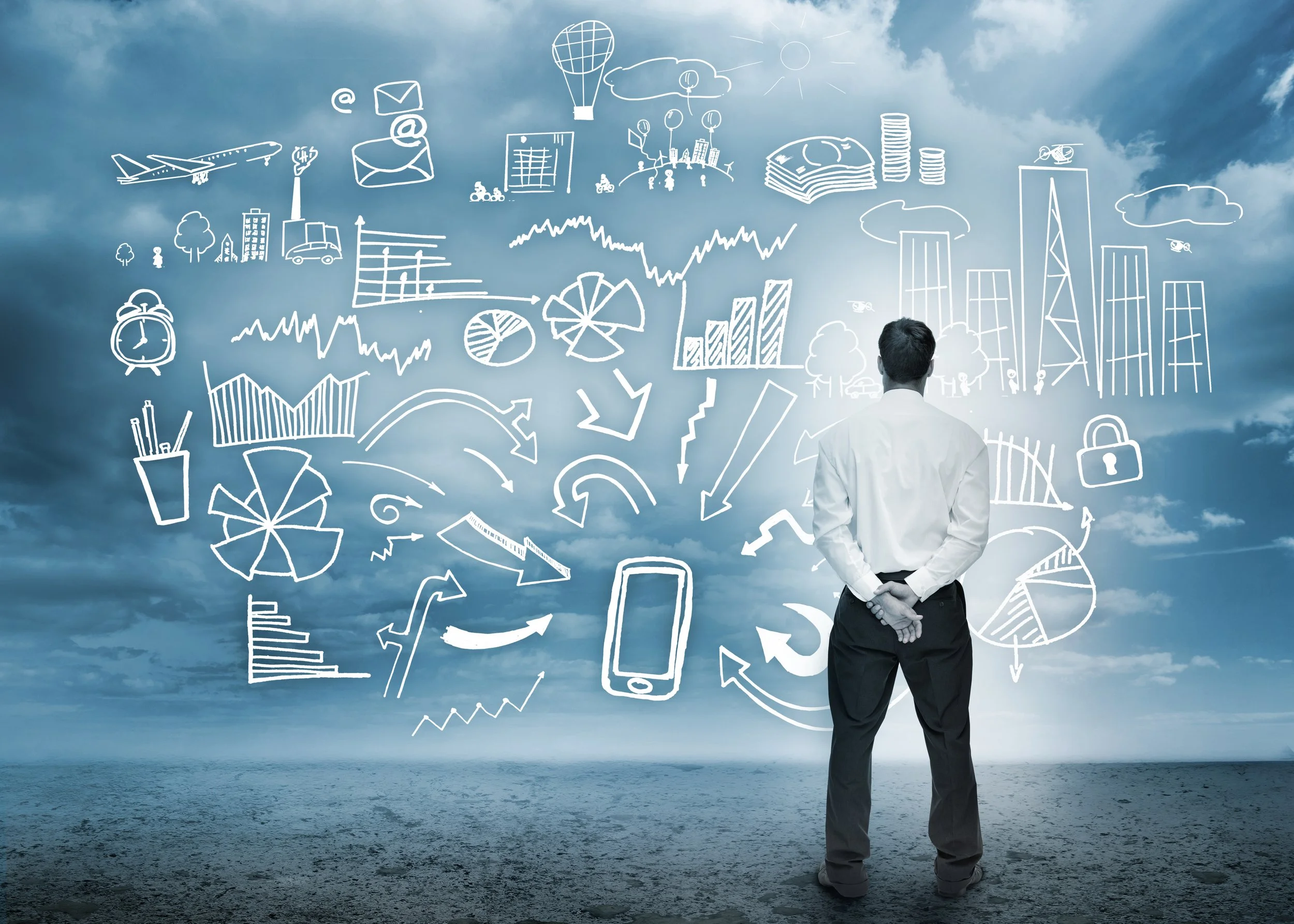 A man in business attire stands on a beach looking at a cloudy sky with white line drawings of graphs, charts, symbols, and icons related to business, finance, and technology overlaid in the sky.