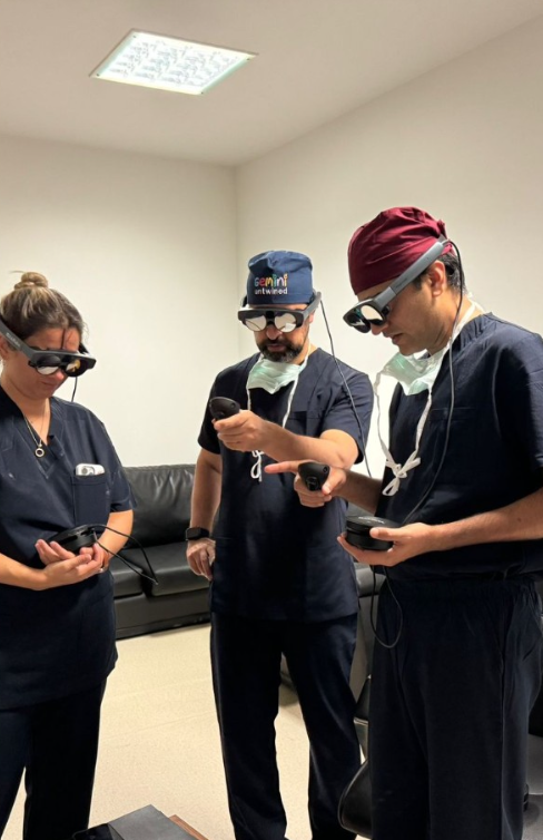 Three healthcare professionals wearing surgical scrubs, night vision goggles, and face masks using handheld electronic devices in a clinical room.
