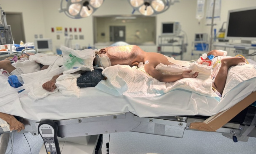 A patient lying on a hospital bed with medical equipment and monitors in the background, appearing to be in critical condition.