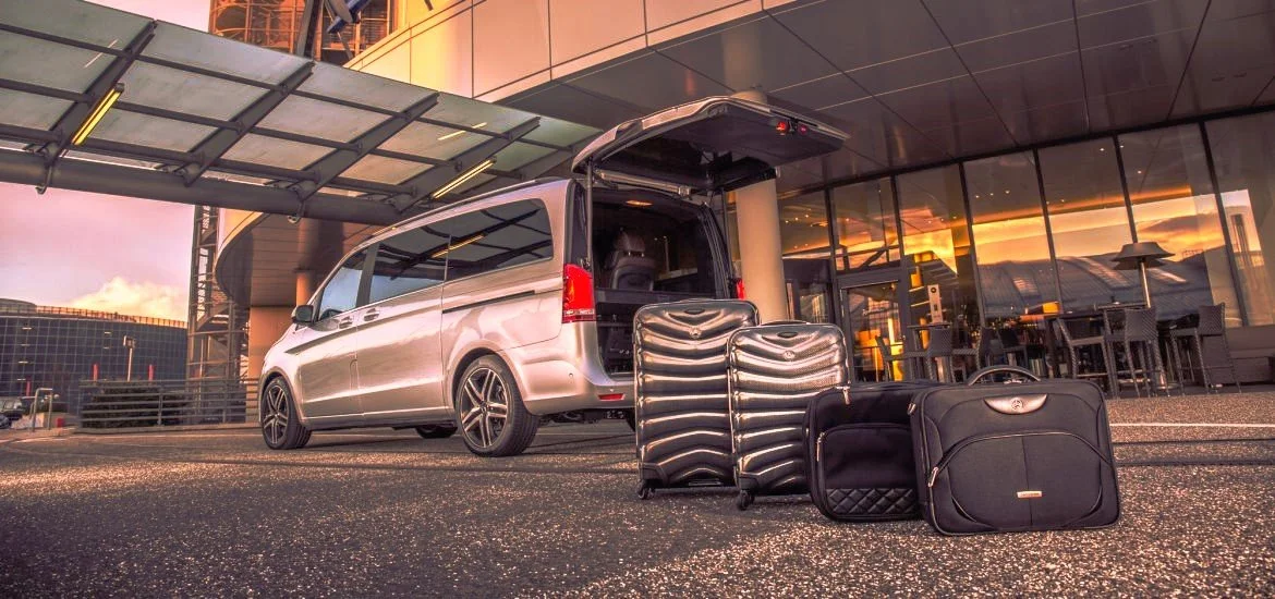 Horizon Dream Villas - Airport Transfer - Car rental concierge - Luggage and a van parked outside a modern building at sunset