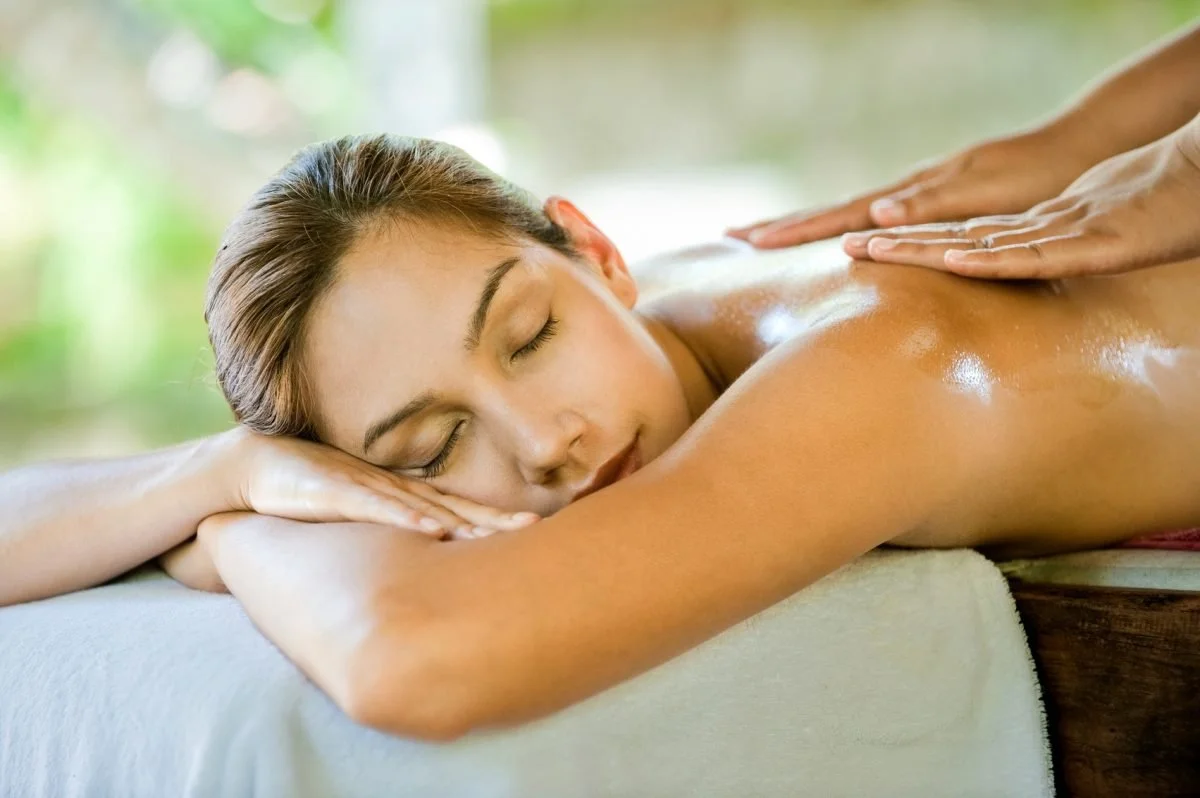 Horizon Dream Villas - Experiences - Private Massage - Woman receiving a back massage and relaxing with her eyes closed.