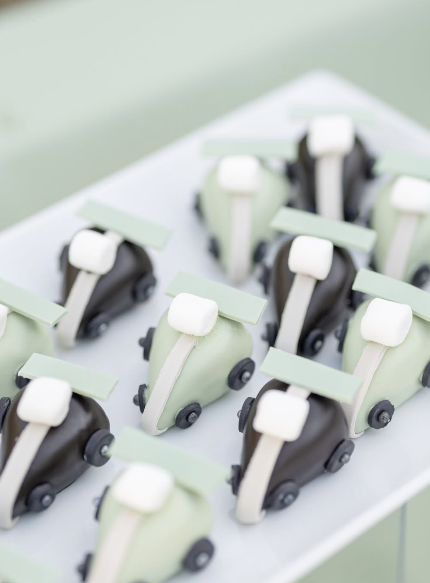 Close-up of miniature toy cars on a white surface, with pastel-colored details and black wheels.