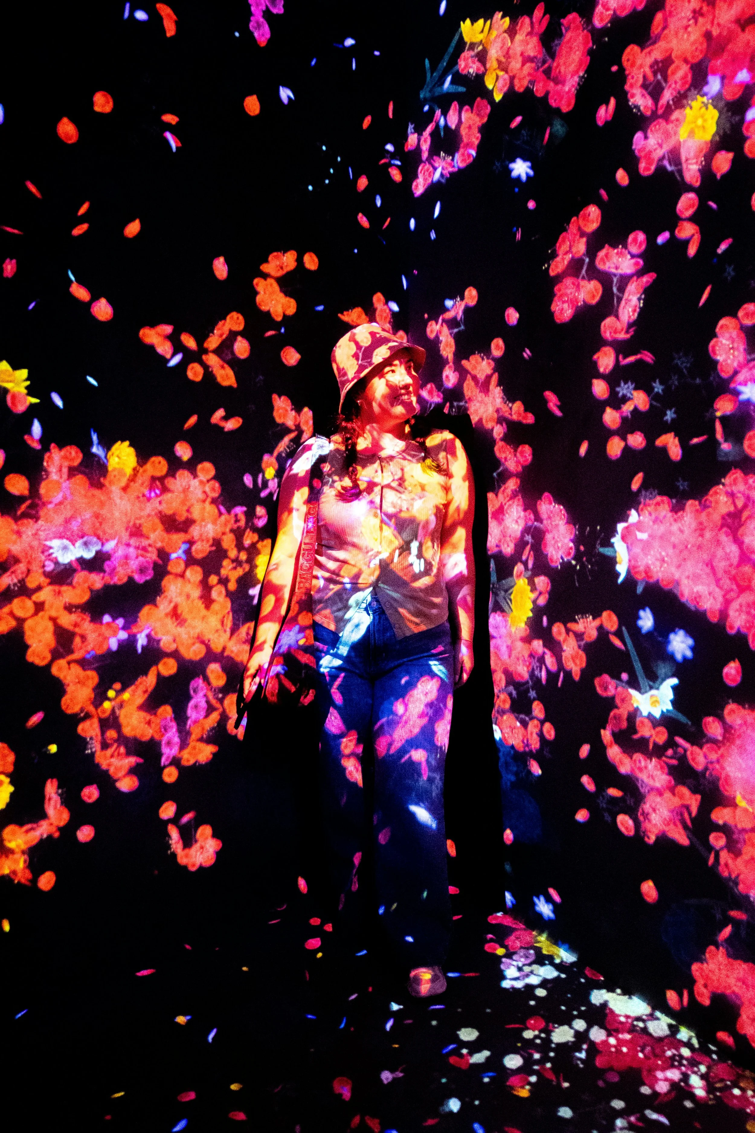 Visitor surrounded by projected flowers in an immersive experience