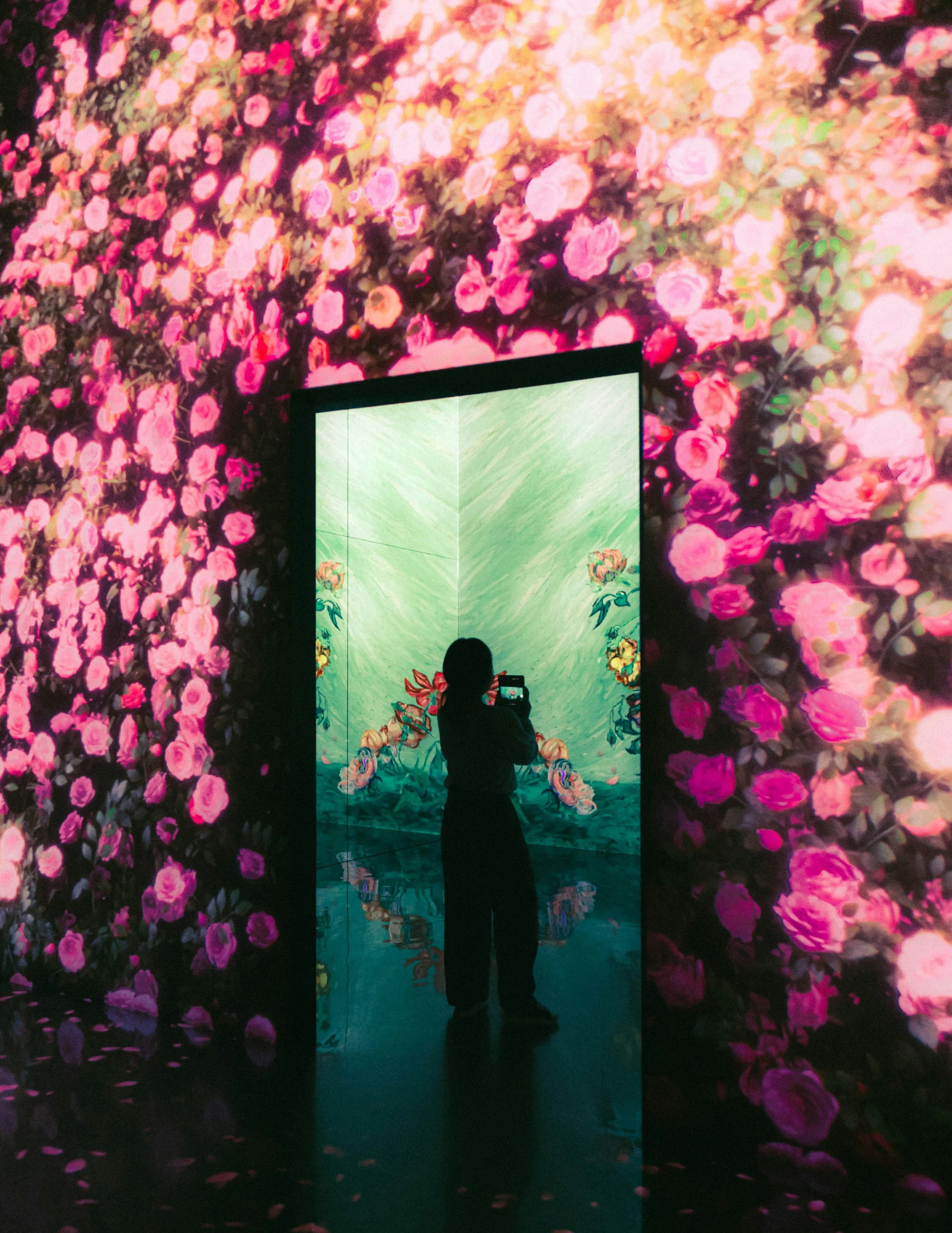 Visitor photographing an immersive floral projection room