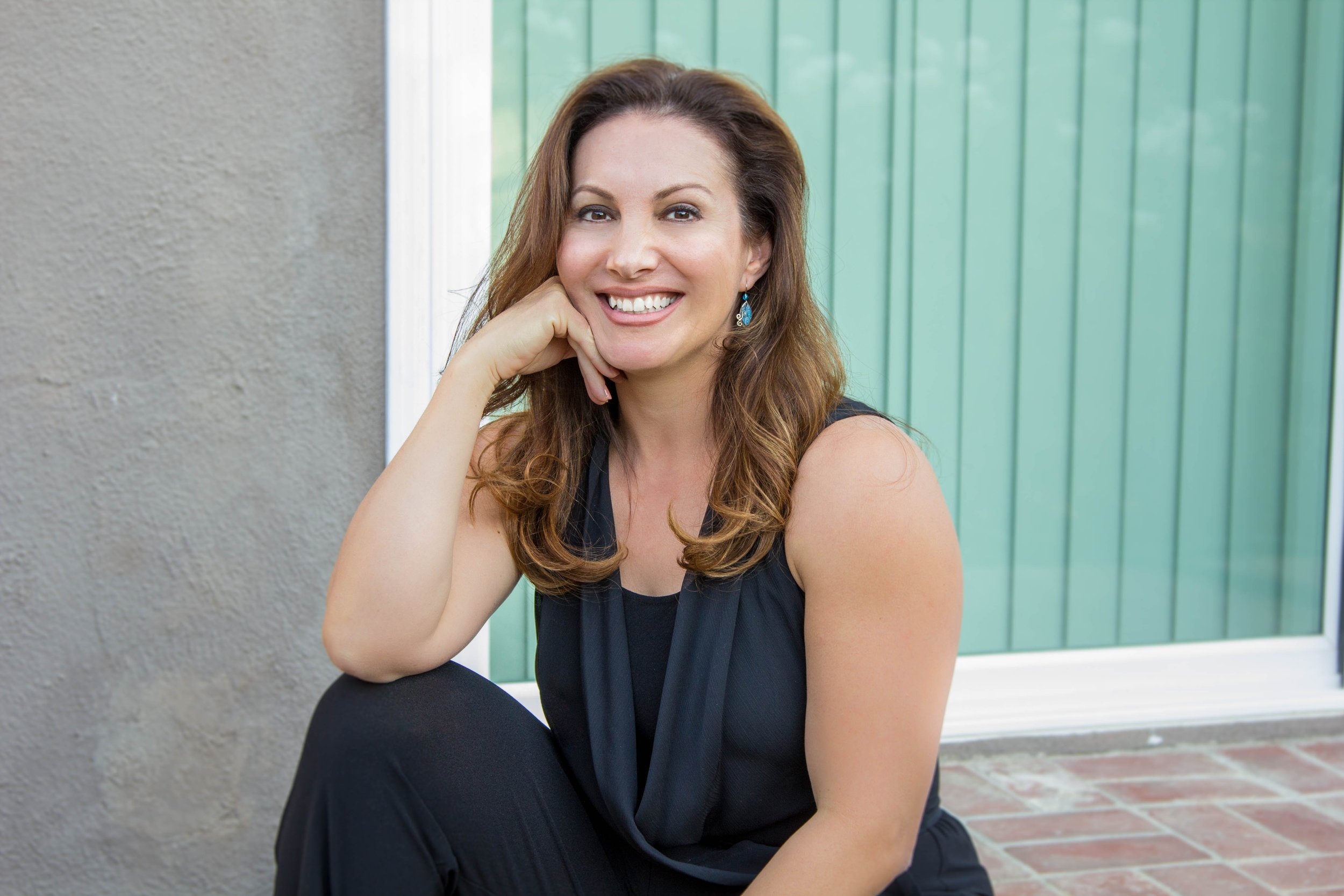 Maribel Dugas, LCSW, Zen & Health, Maribel smiling, wearing a black dress, residential background, green and brown frame on picture