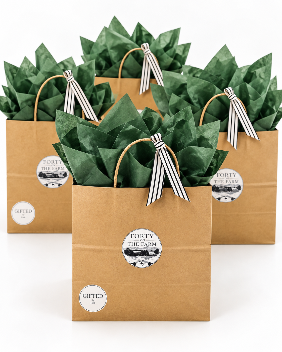 Three paper gift bags labeled 'Forty on the Farm' with green tissue paper and black-and-white striped ribbons inside.