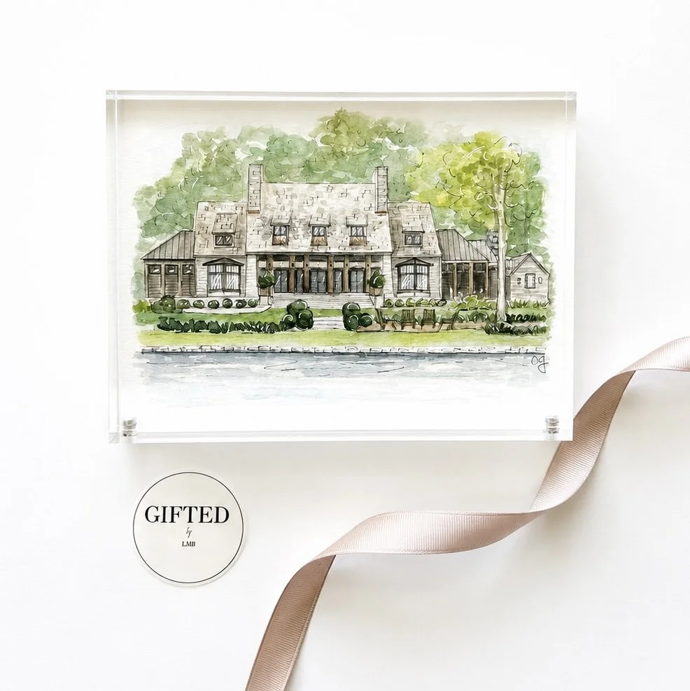 A watercolor illustration of a large house with a gray roof, surrounded by green trees and bushes, sitting beside a body of water.