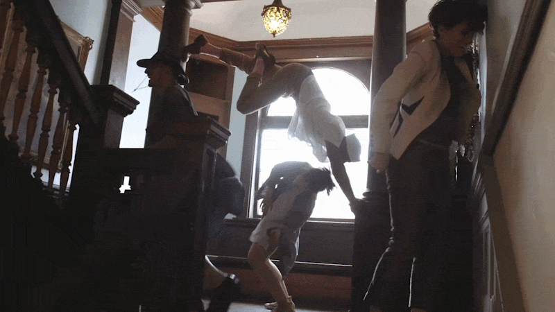 A woman doing a back handspring on a staircase with three other women observing.
