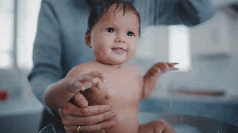Baby being bathed in a sink by an adult
