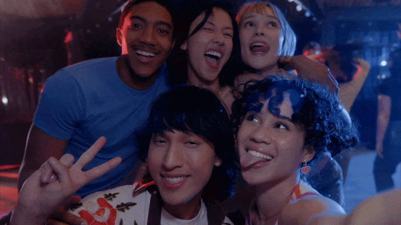 Group of five young friends taking a selfie at a party, smiling and having fun.