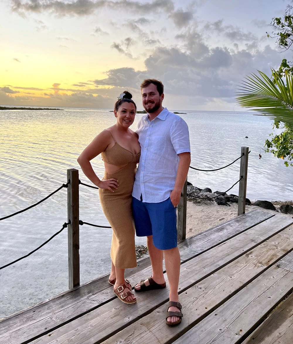 Stephanie and her husband at sunset on a wooden dock over the lagoon on a Bora Bora motu