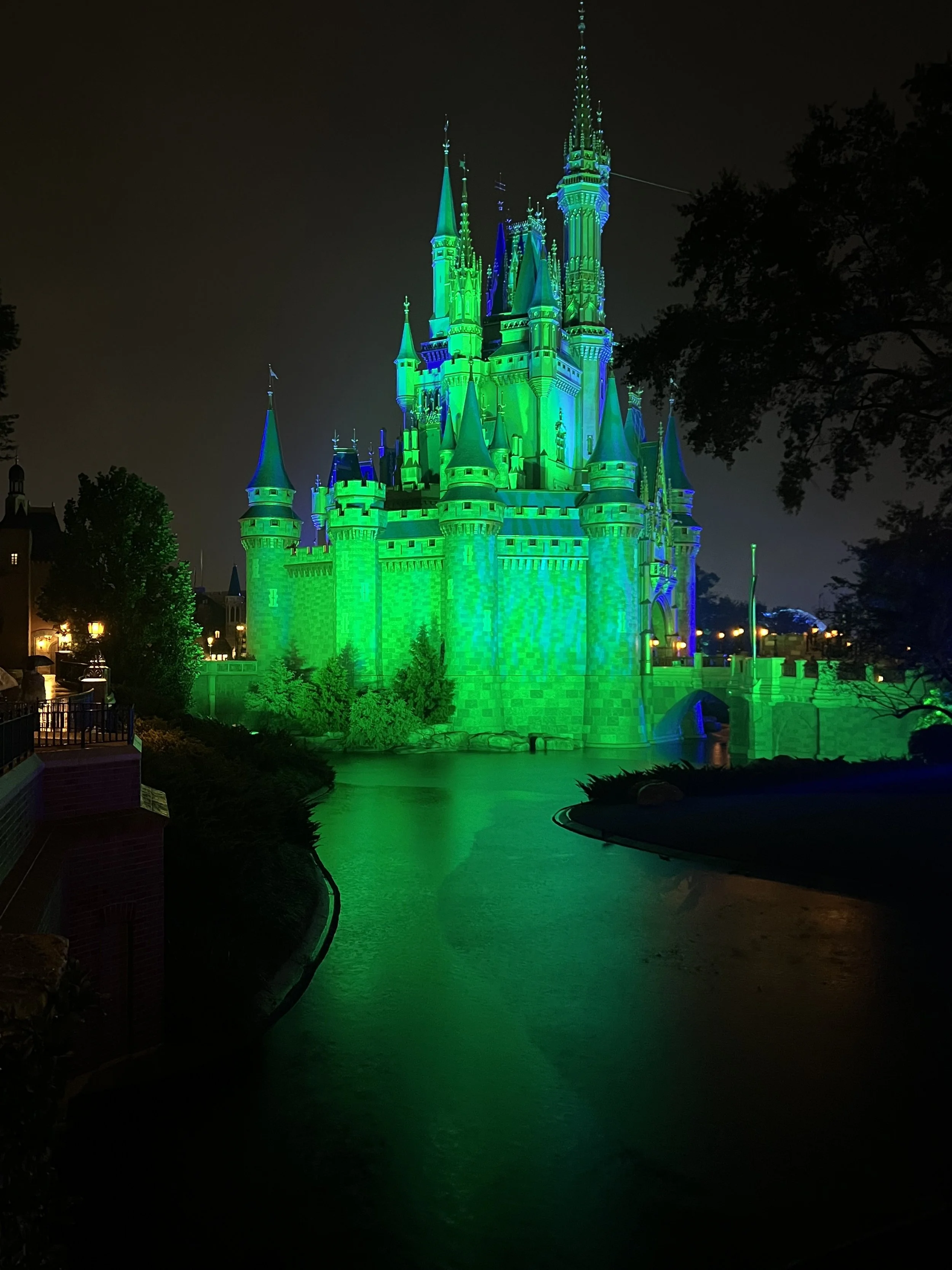 Cinderella Castle lit green for Halloween at night.