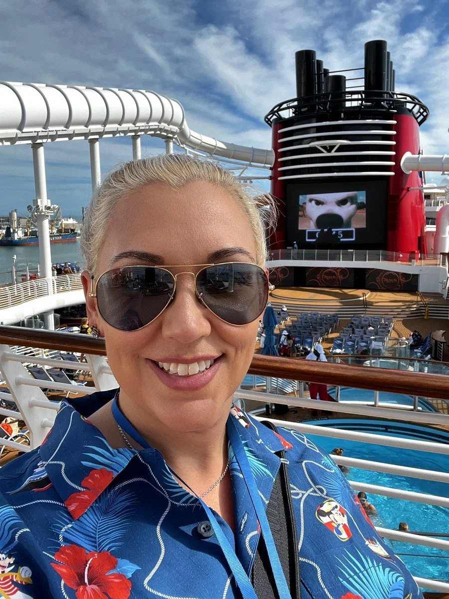 Stephanie smiling on deck of the Disney Treasure with the ship’s red funnel behind her