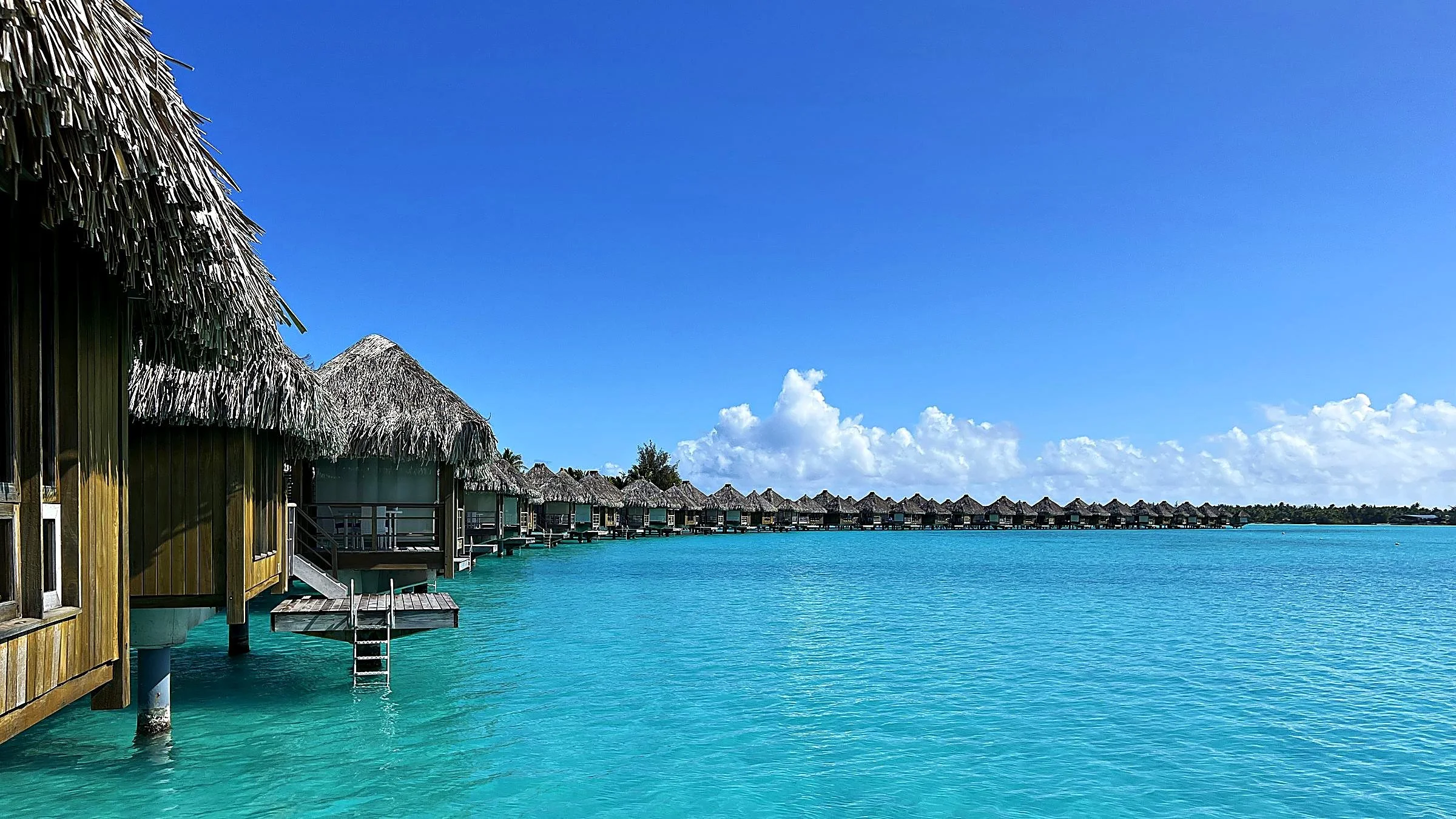 Row of thatched overwater bungalows above a turquoise lagoon in Bora Bora