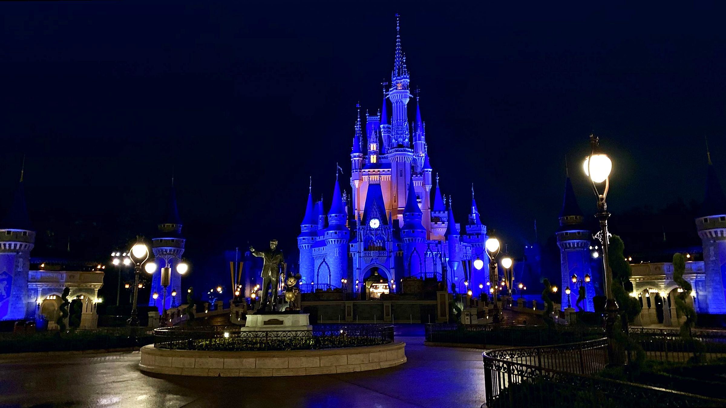 Cinderella Castle lit in blue at night with the Partners statue in front
