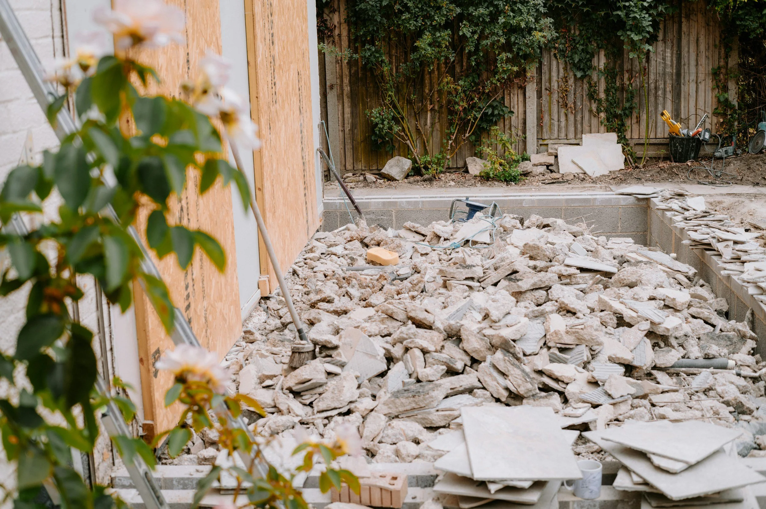 A concrete patio demolition and home renovation project in a residential backyard.