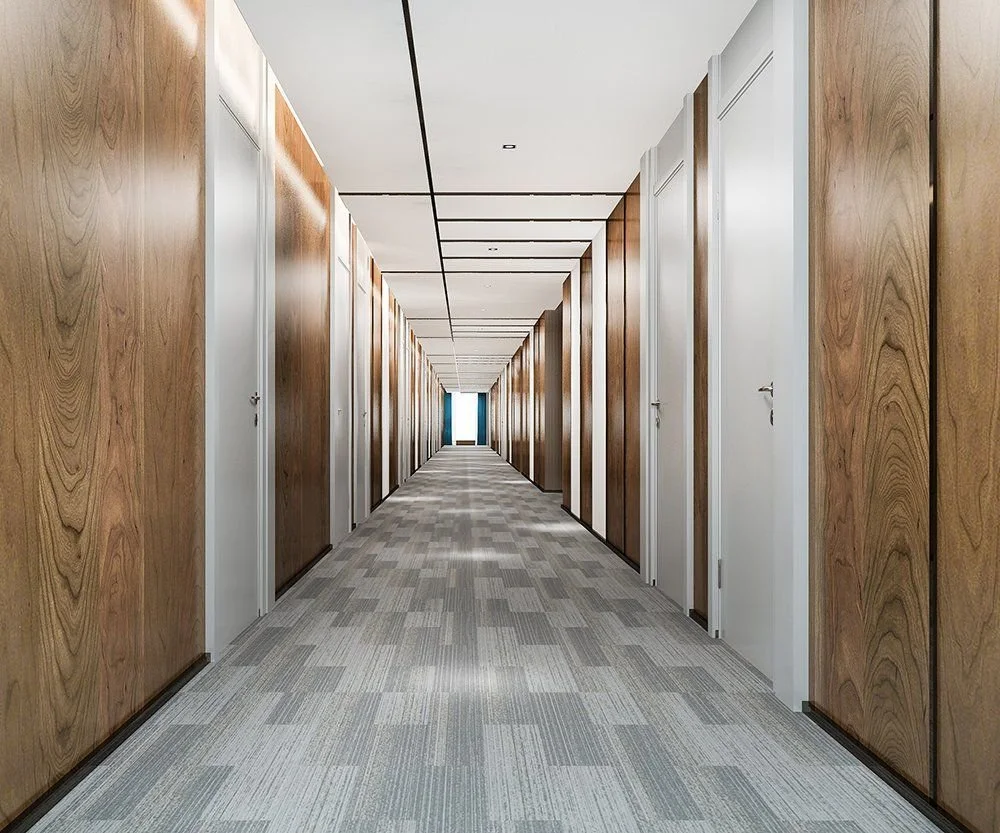 Long hallway with white ceiling, brown wooden wall panels, and white doors, leading to a bright window at the end.