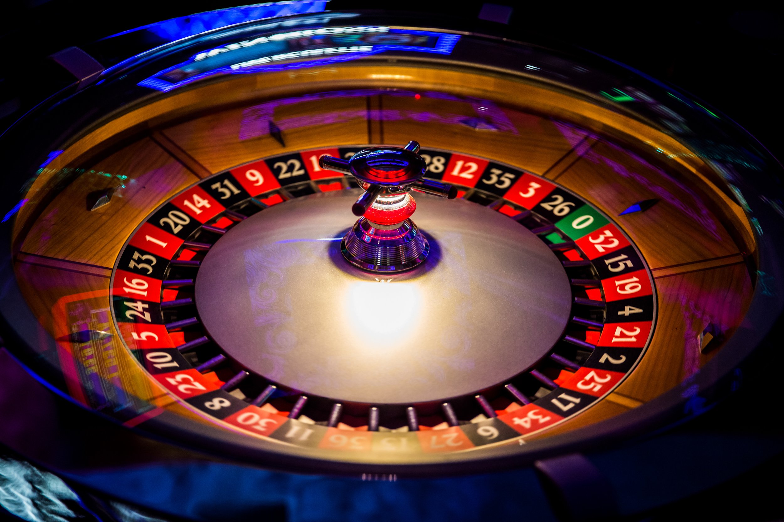 Close-up of a roulette wheel spinning at a casino, showing the numbered pocket and the ball in motion, with colorful reflections and lighting.
