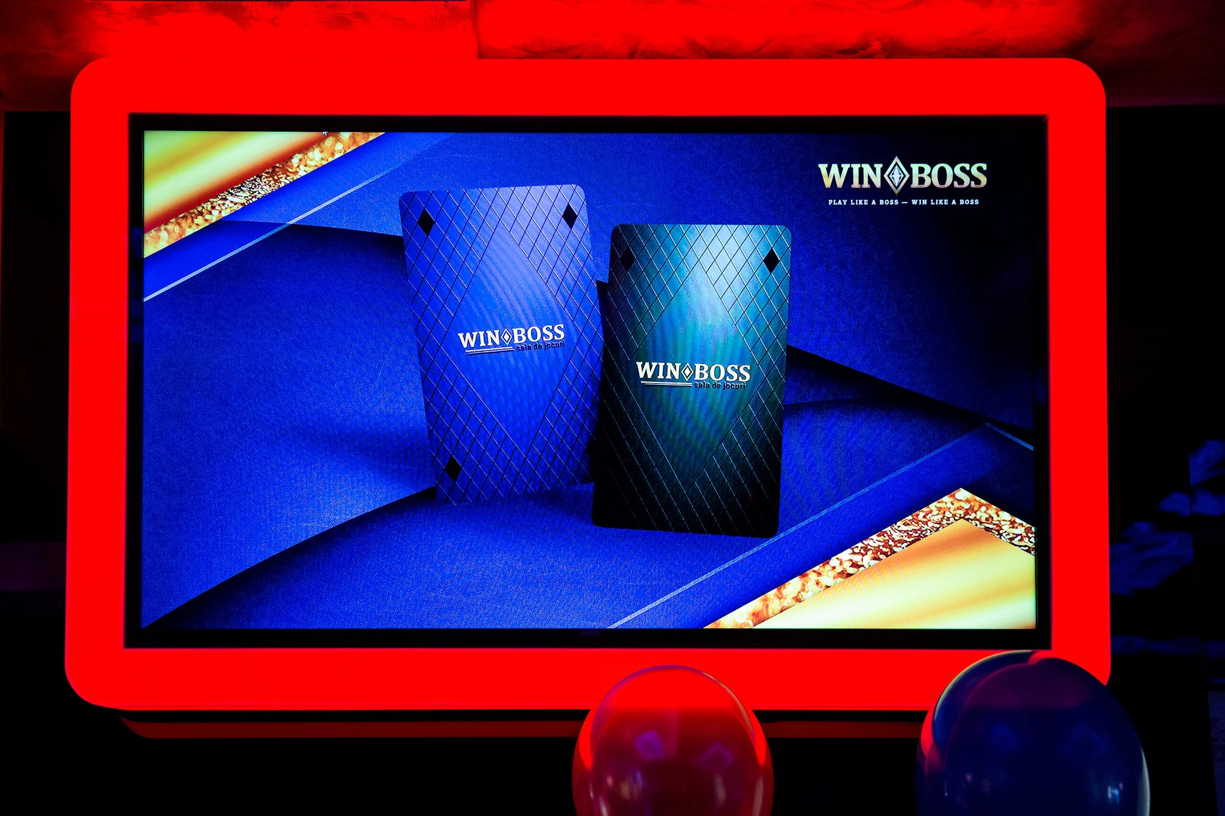 Digital display featuring an advertisement for WIN BOSS, showcasing two metallic, diamond-patterned objects with the WIN BOSS logo and slogan 'Play Like a Boss — Win Like a Boss.'