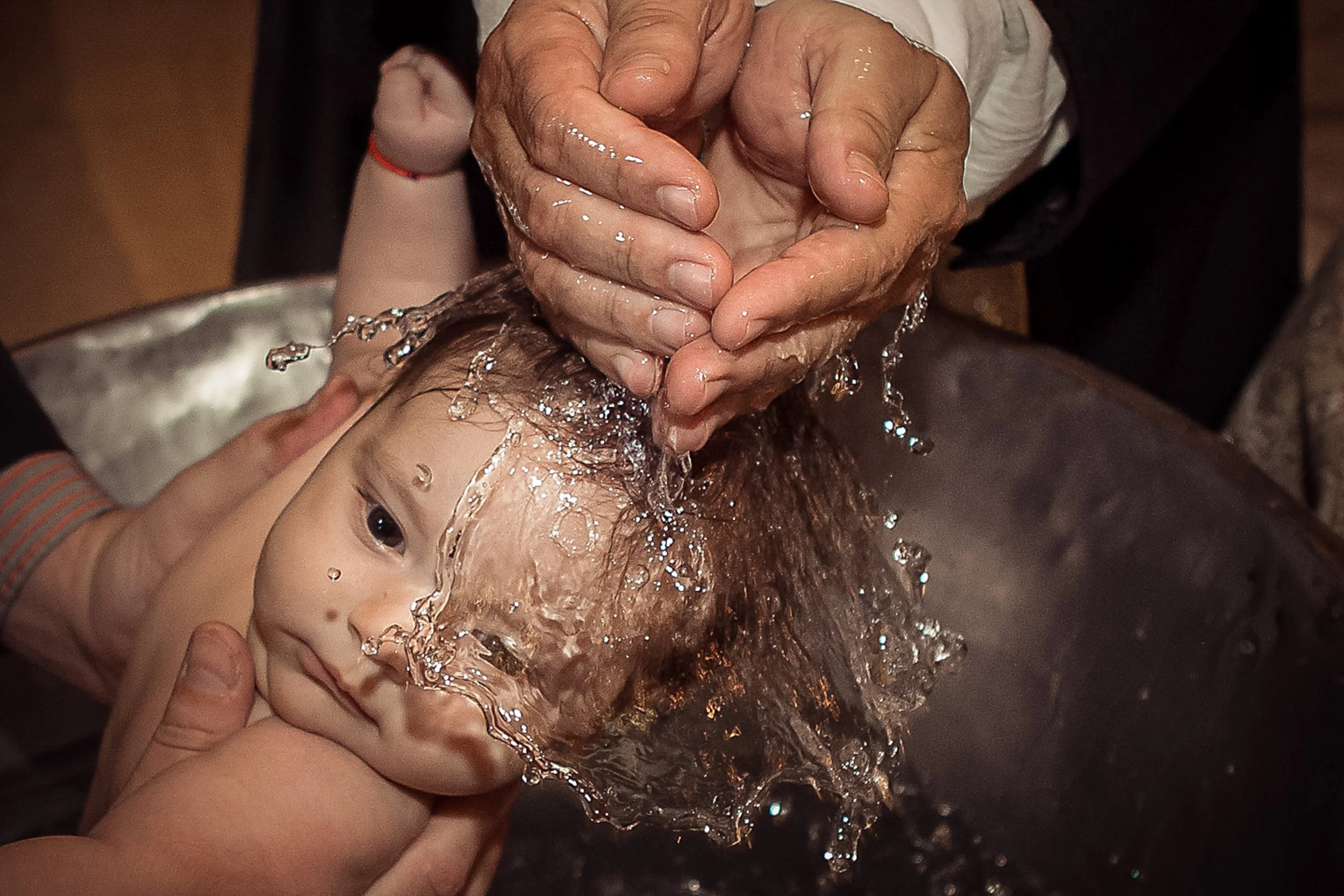 People washing a child's head with water.