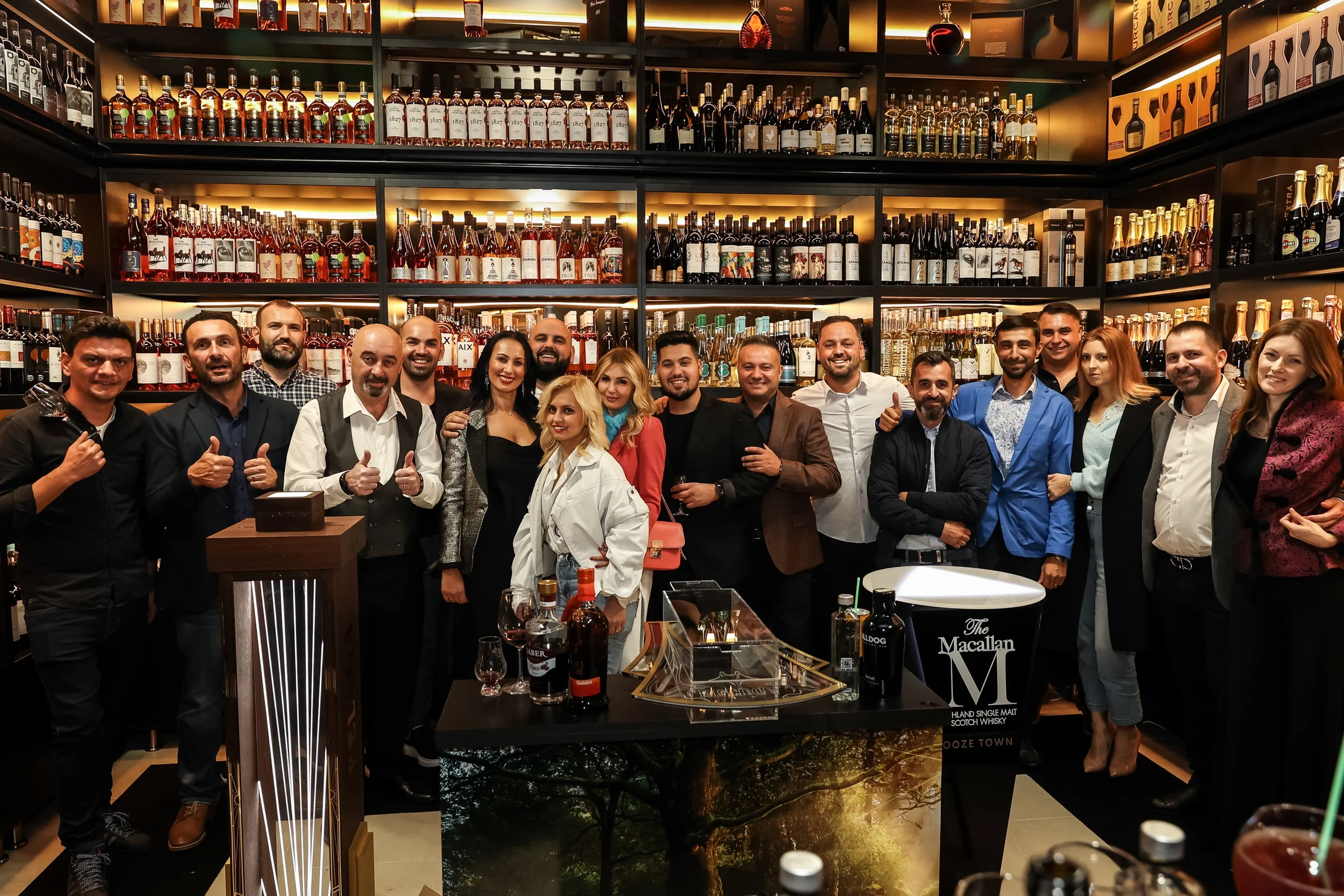 Group of people celebrating at a bar or liquor store with shelves full of various bottles of alcohol in the background.