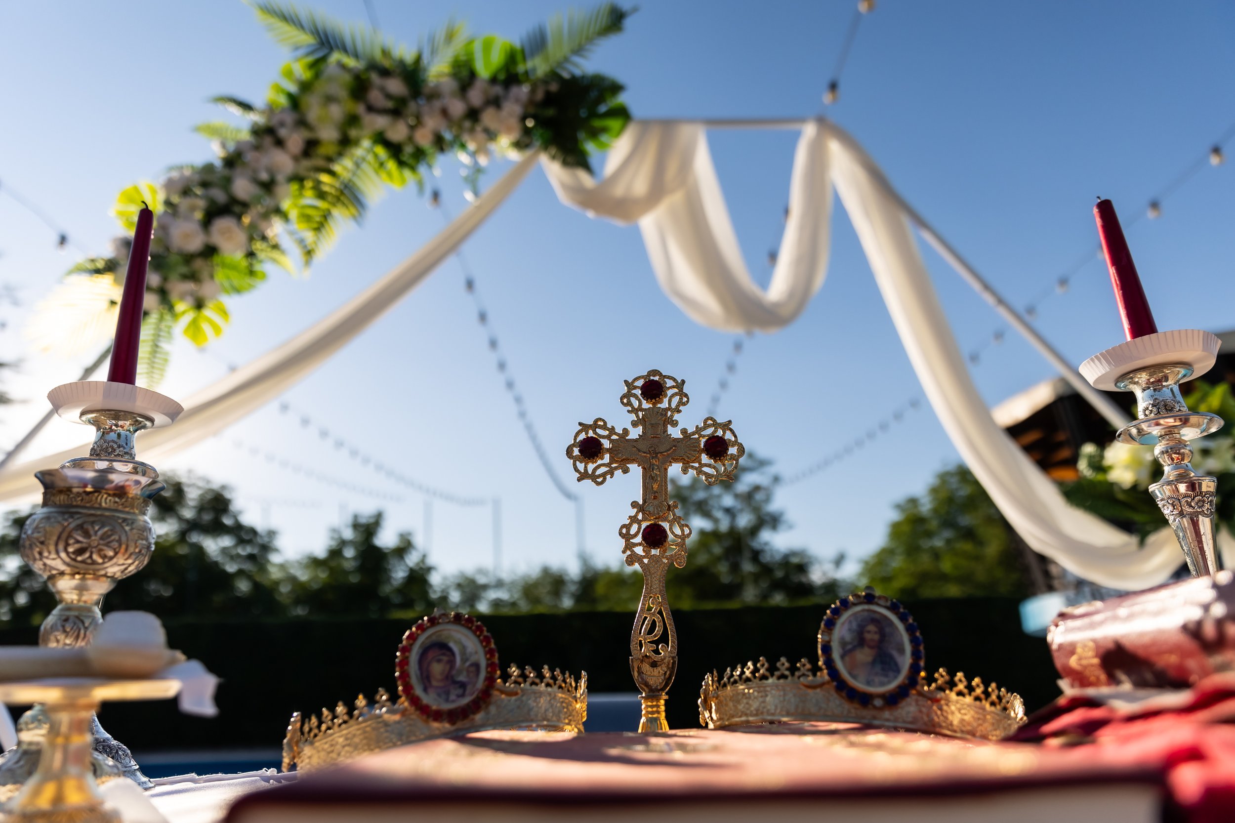 Decorated altar with religious icons, candles, and floral arrangements for a celebration or religious ceremony outdoors on a clear sunny day.