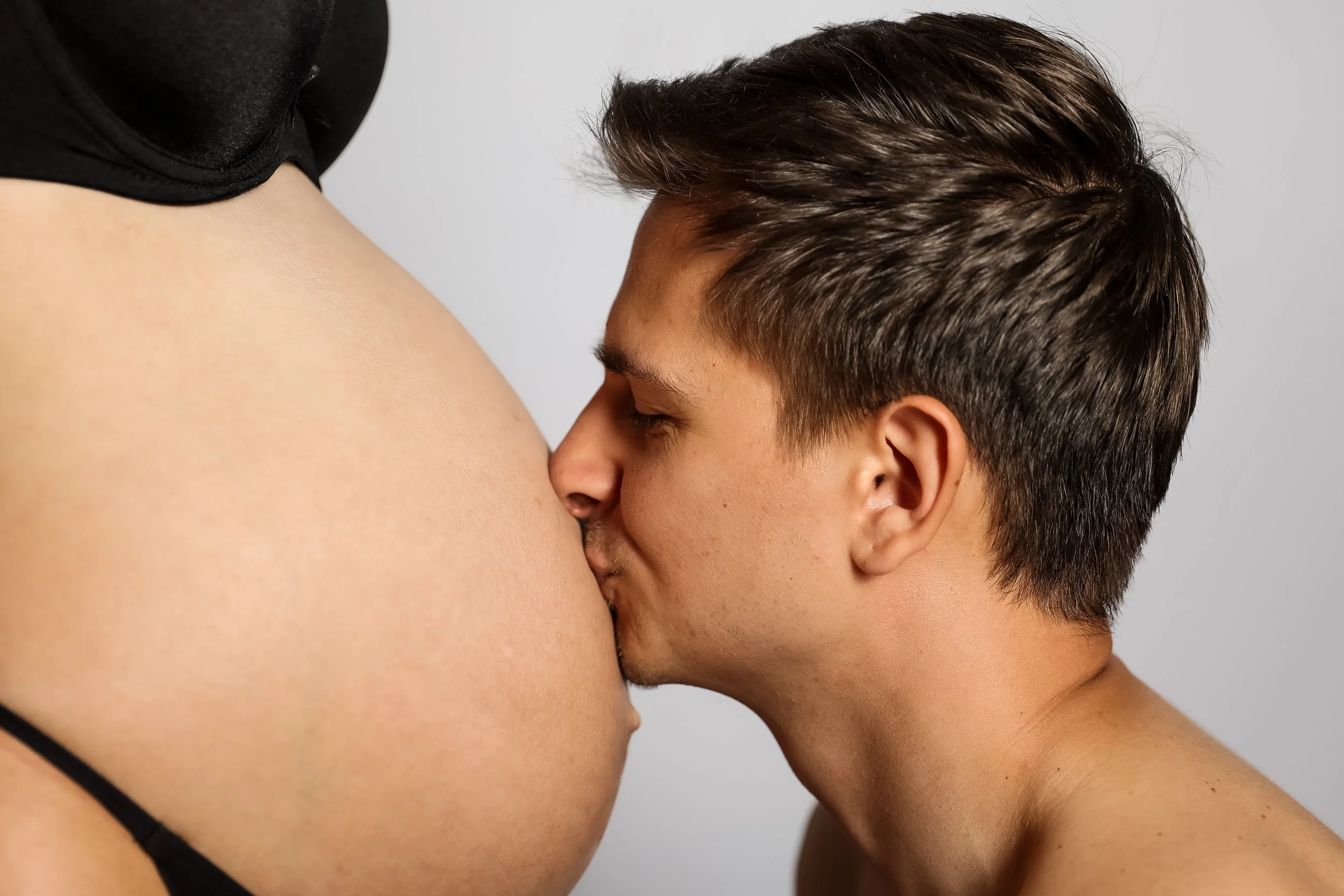 A person with dark short hair and another person with light skin and dark hair are engaging in a close, intimate moment.