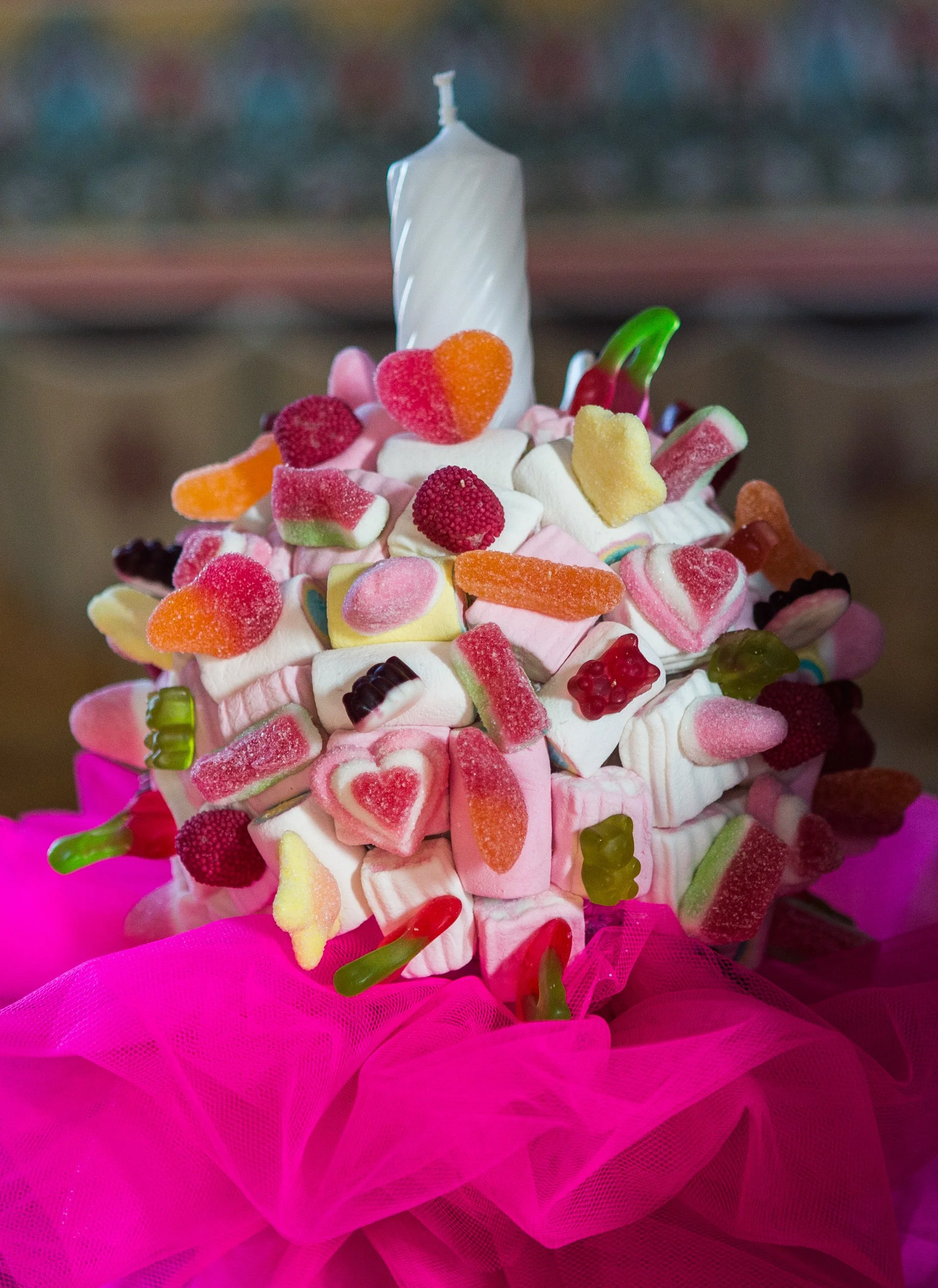 Colorful bouquet of assorted candies and marshmallows decorated with pink tulle fabric.