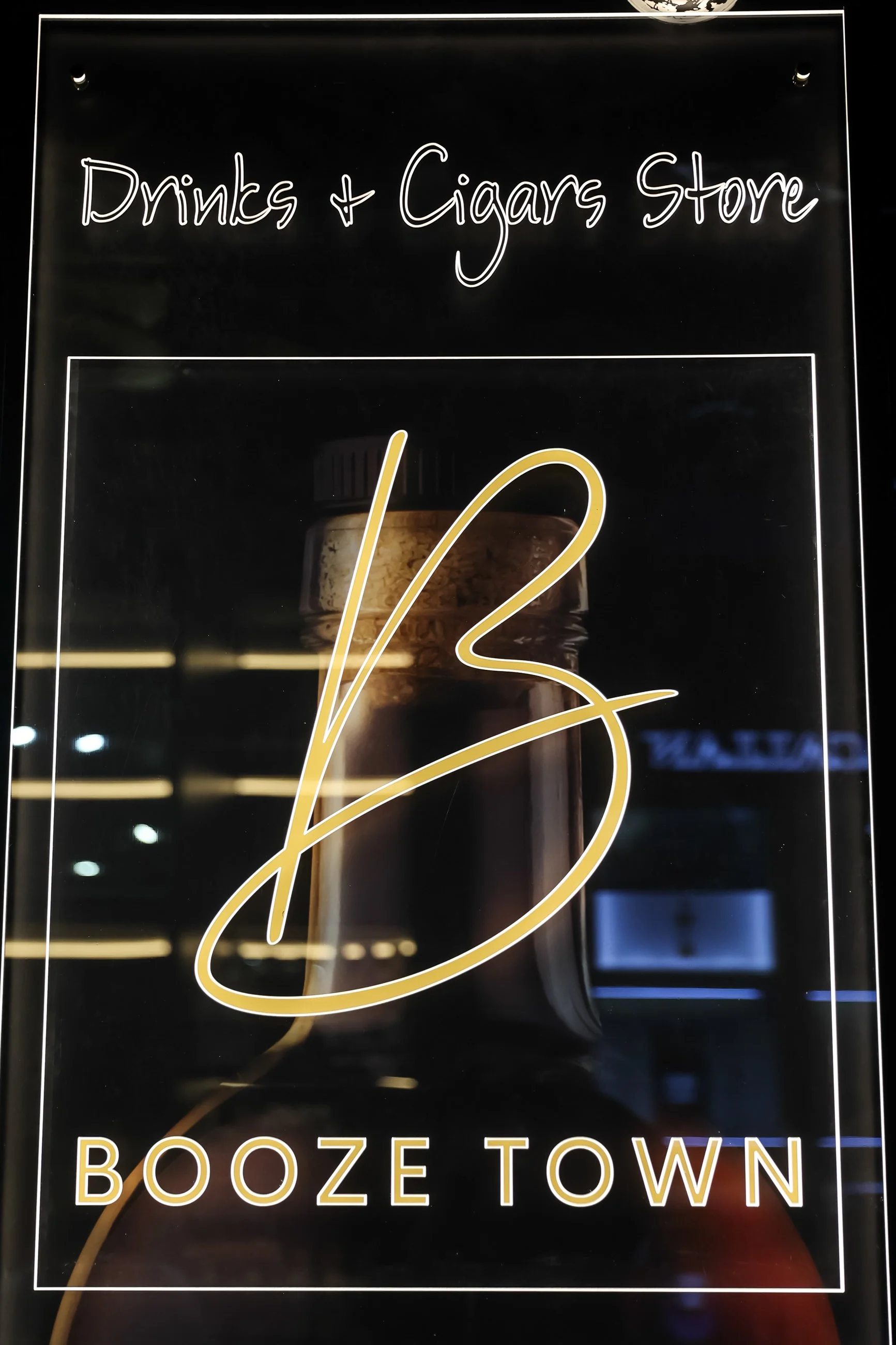 A sign for a store called Booze Town that sells drinks and cigars, with a background image of a bottle of liquor.