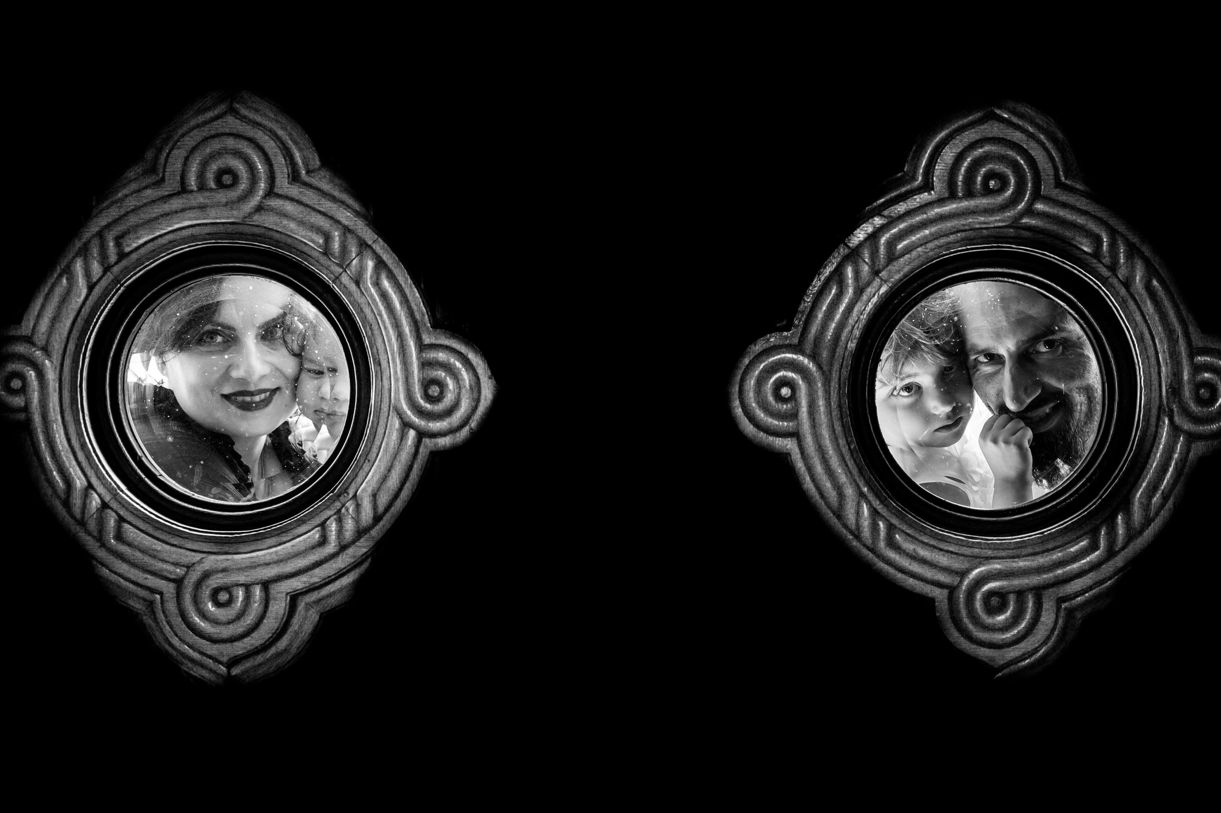 Black and white photo of a mirror with an ornate frame reflecting a woman with dark hair and lipstick and a child with light hair.
