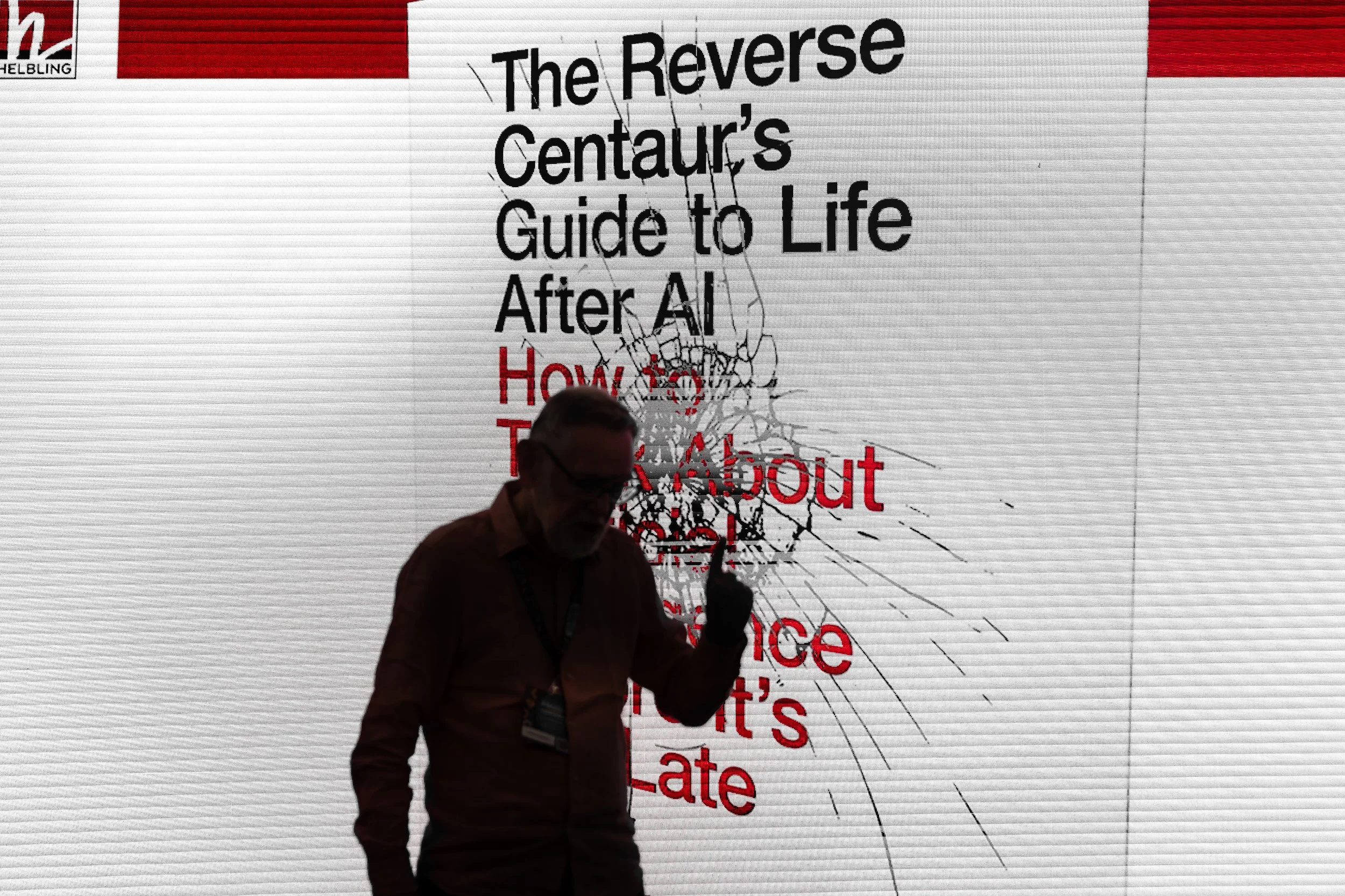 A person holding a microphone, standing in front of a large screen displaying text with a cracked glass effect.