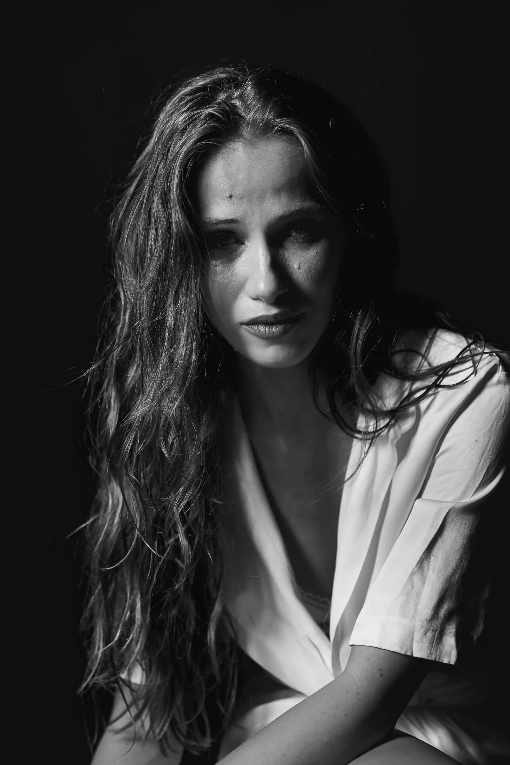 Black and white portrait of a woman with long, curly hair and wet skin, looking directly at the camera with a serious expression.
